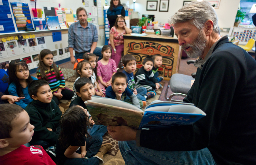 In this file photo taken in November 2014, Juneau photographer Mark Kelley reads to students in teacher Kitty Eddy’s K-1 Tlingit Language and Culture Classroom from his recently released book titled “Once Upon Alaska: A Kids Photo Book” at Harborview Elementary School.