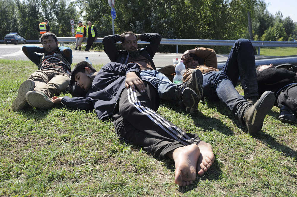 Captured migrants rest near the M5 motorway on the outskirts of the border village of Roszke, 180 kms southeast of Budapest, Hungary, Monday, Sept. 21, 2015. (Zoltan Gergely Kelemen/MTI via AP)