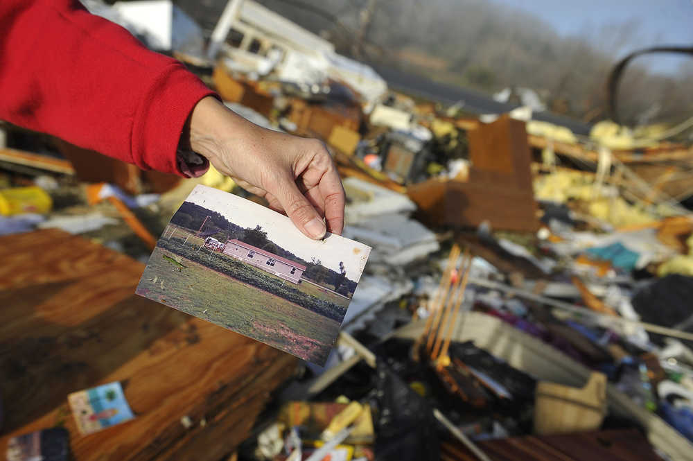 Diana Davis shows a photo she found in the rubble of her father-in-law's home after Wednesday's tornado in Lutts, Tenn., Thursday, Dec. 24, 2015. The photo shows what the house looked like before the tornado hit the area. (Larry McCormack/The Tennessean via AP) MANDATORY CREDIT