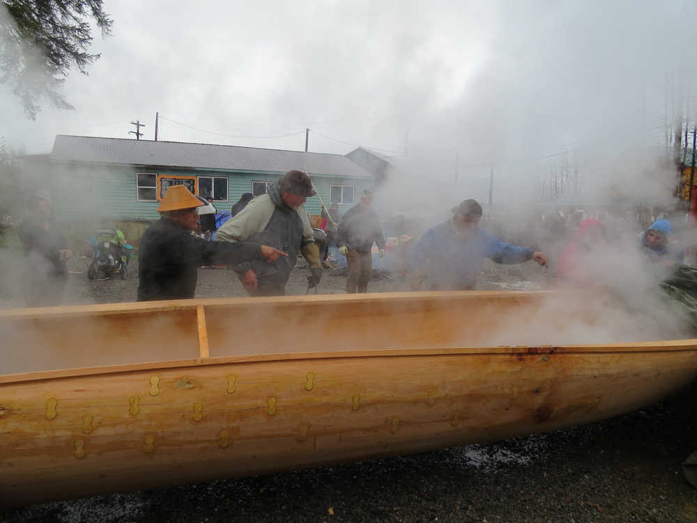 Wayne Price directs Pete Schneeberger and Owen James on where to place the heated rocks in the canoe.