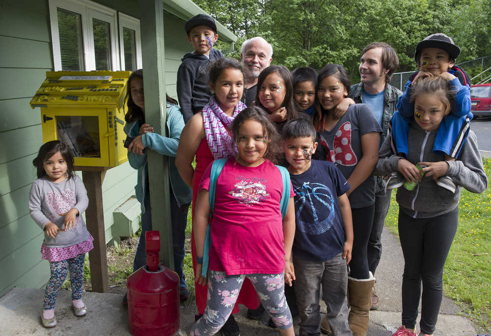 Jim Fowler, back center, poses with children next to a small library they decorated at the Geneva Woods housing complex Wednesday. Fowler has been helping youth with art projects since 1998.