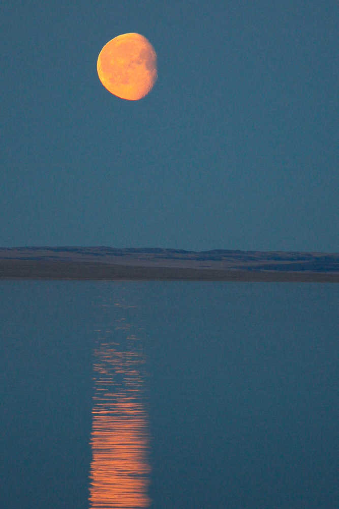 Not to be outdone by the sun, the nearly full moon rises like a giant orange saucer over Simpson Strait.