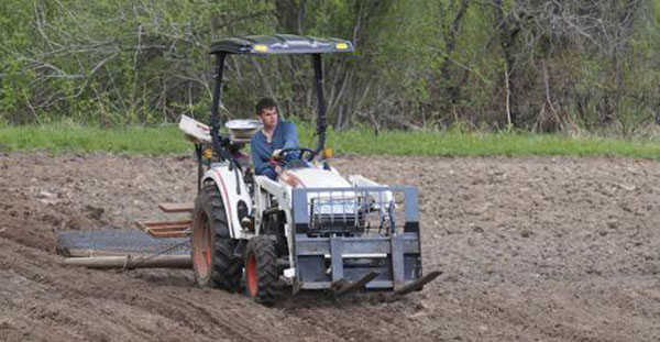 Tim drives a tractor for the first time post-stroke. He is raking George Campbell's potato field before planting commences in May 2014.