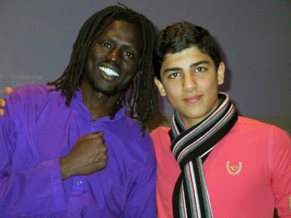 Emanuel Jal and Thunder Mountain High School exchange student Mahmoud Abu Aisha pose for a photo on stage.