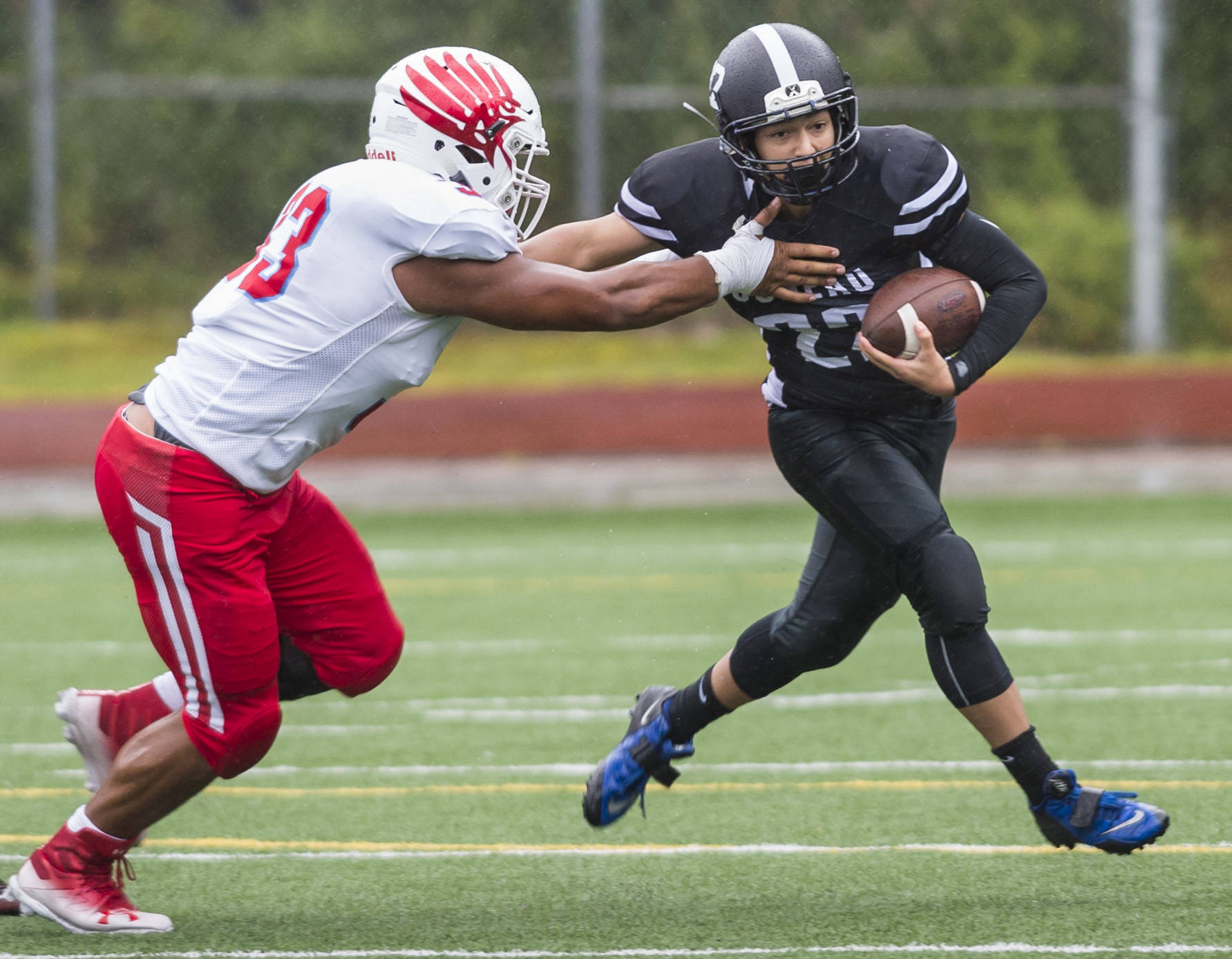 Juneau Football’s Ali Beya, right, is tackled by East’s Earl Apineru at Adair-Kennedy Memorial Field on Saturday, Aug. 25, 2018. East won 40-0. (Michael Penn | Juneau Empire)