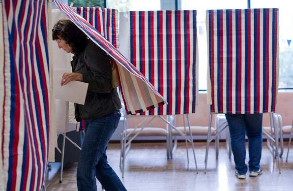 in this file photo from August 2012, Barbara Lobdell ducks into a voting booth at the Douglas Public Library for the state primary election.