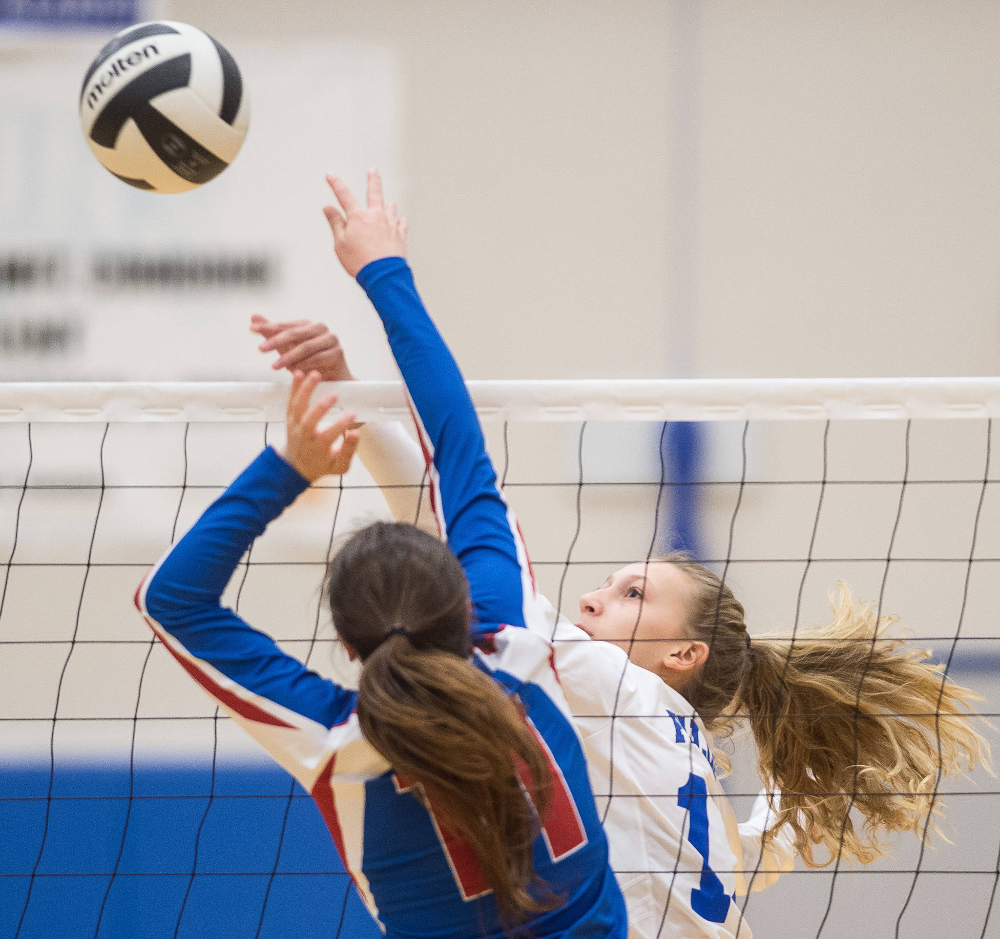 Thunder Mountain’s Lilyan Smith tips the ball over against Sitka’s Hadley Andersen at Thunder Mountain High School on Friday. (Michael Penn | Juneau Empire)