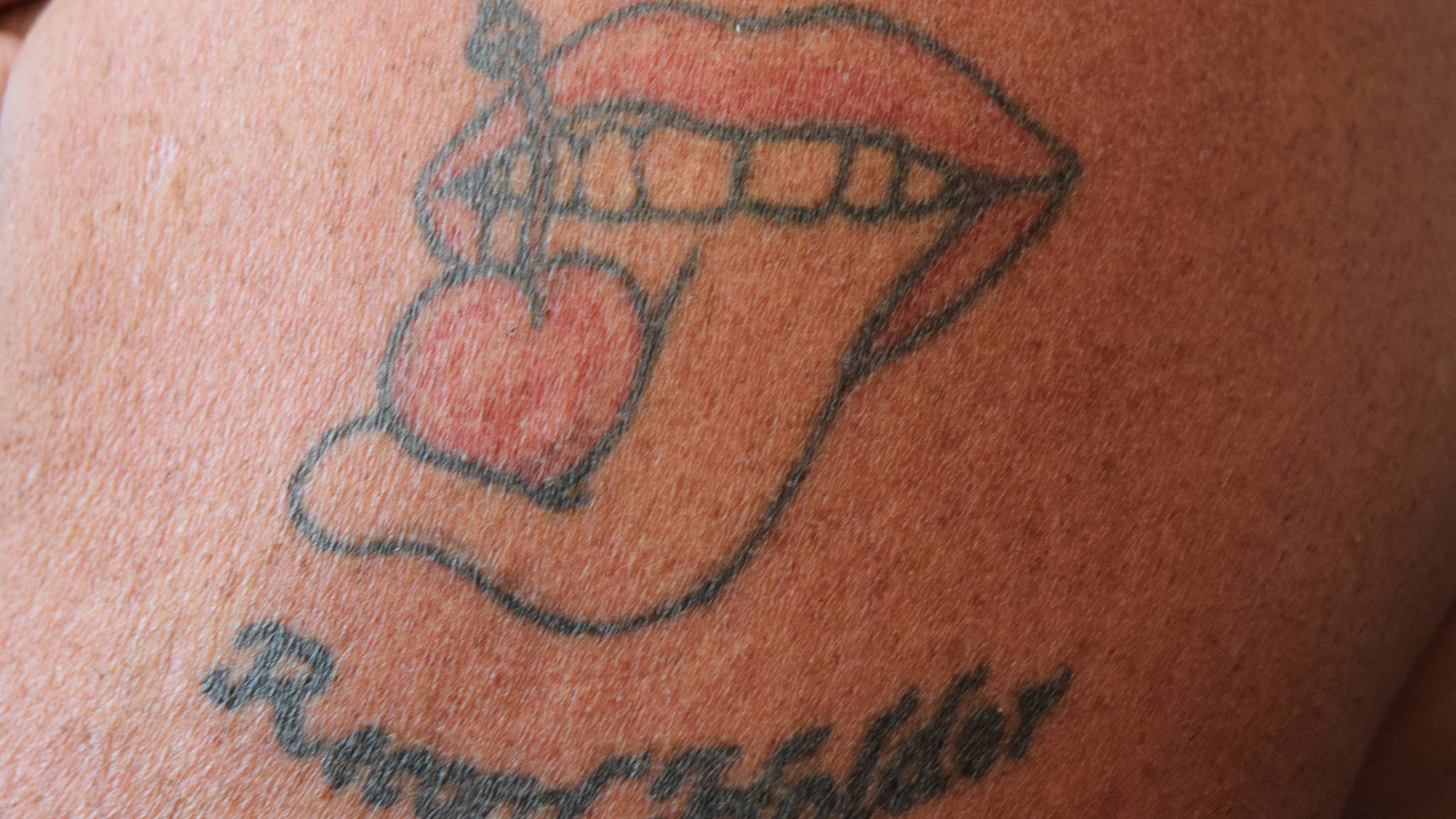 Al Gliniecki’s tattoo of his trademarked logo of a cherry with its stem tied on an outstretched tongue. (Nolin Ainsworth | Juneau Empire)