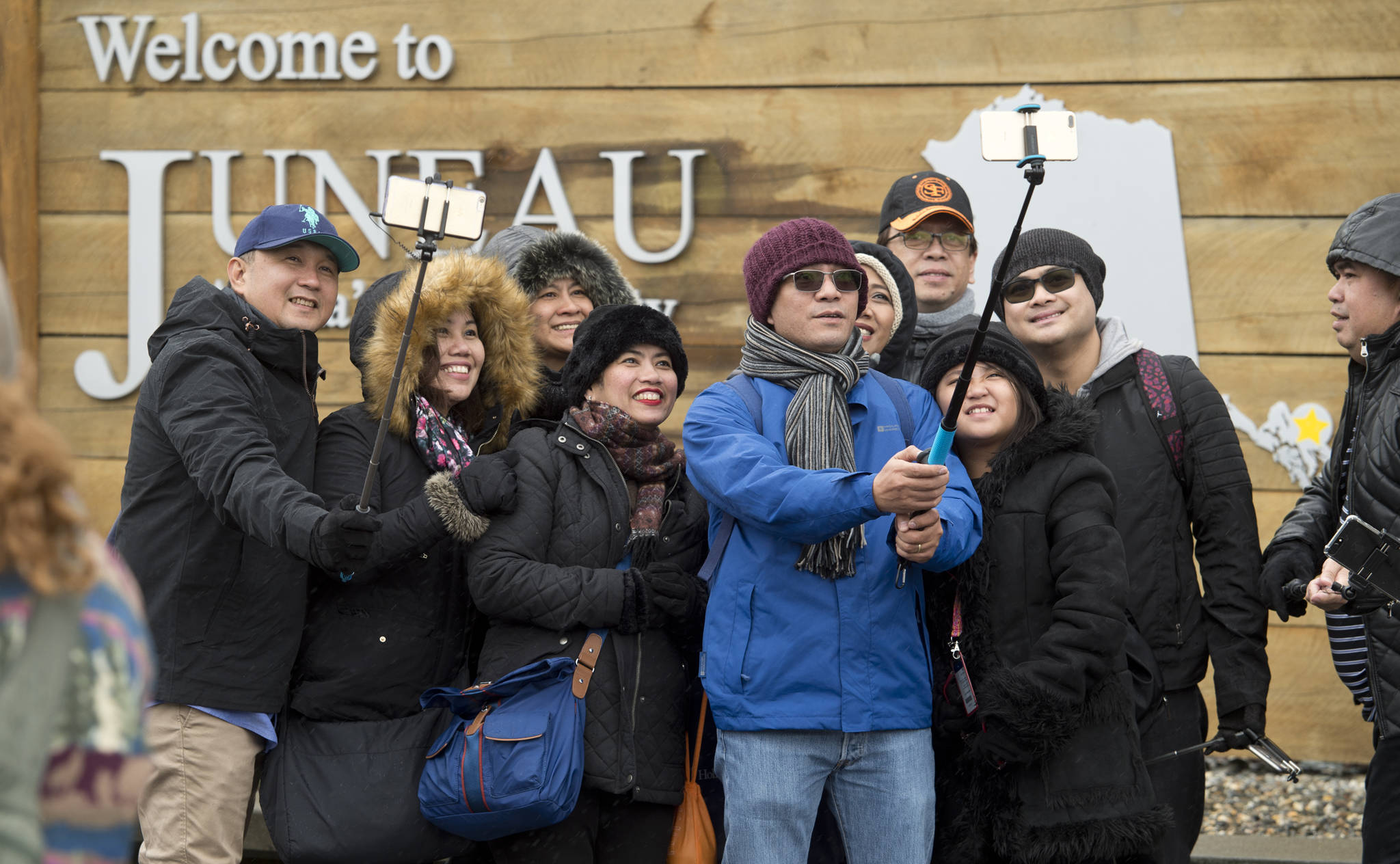 In this May 1 photo, tourists line up with their selfie sticks in front of the “Welcome to Juneau” sign after arriving by the first cruise ships of the season. (Michael Penn | Juneau Empire File)