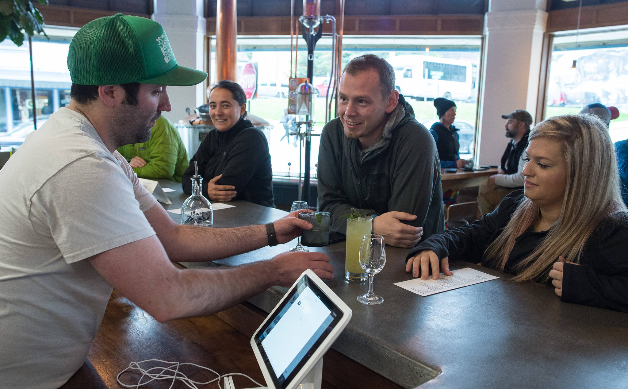 Brandon Howard, a cofounder of Amalga Distillery, left, serves mixed drinks to Nick Thein and Terra Veler at the distillery’s tasting room at Franklin and Second Streets on Thursday, Sept. 14, 2017. Rep. Chris Tuck, D-Anchorage, has proposed a bill that would allow the distillery to keep serving cocktails. (Michael Penn | Juneau Empire file)