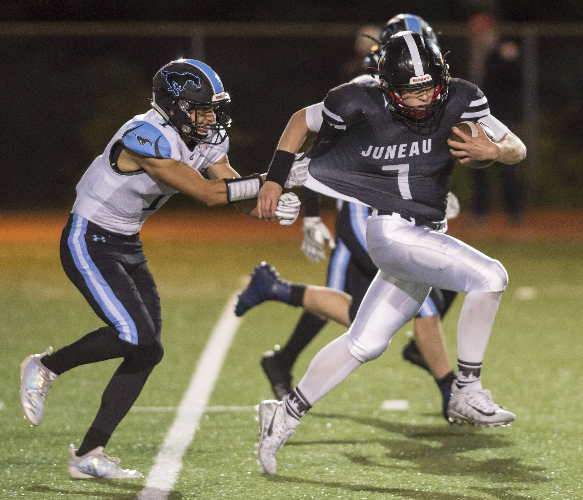 Juneau United’s Cooper Kriegmont, right, is slowed down by Chugiak’s Brandon O’Fihelly at Adair-Kennedy Memorial Field on Friday, Sept. 14, 2018. Chugiak won 22-7. (Michael Penn | Juneau Empire)