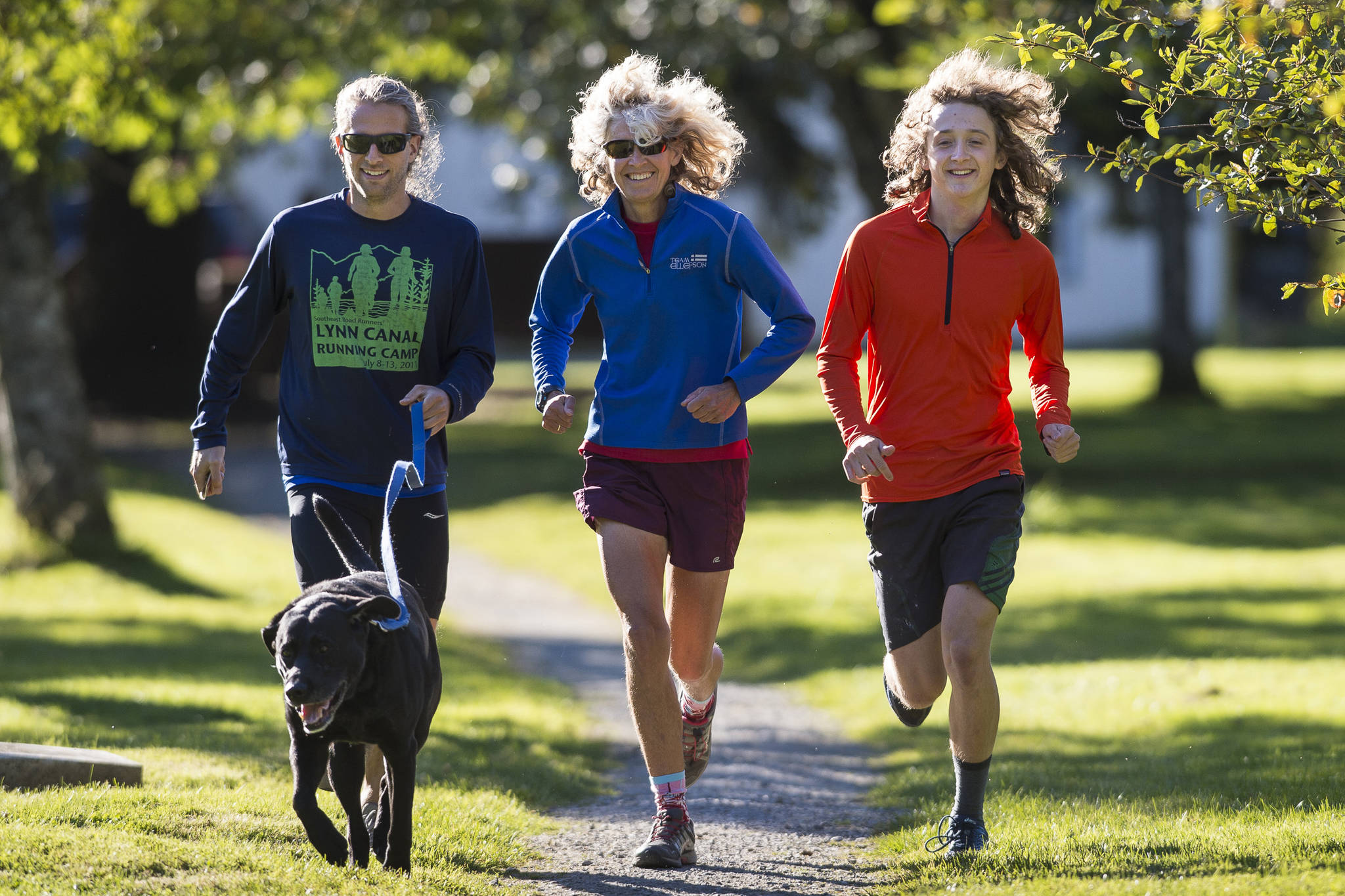 Merry Ellefson, center, runs with her son, Arne Ellefson-Carnes, right, and co-coach Tristan Knutson-Lombardo during Juneau-Douglas High School cross country practice on Wednesday, Sept. 19, 2018. (Michael Penn | Juneau Empire File)