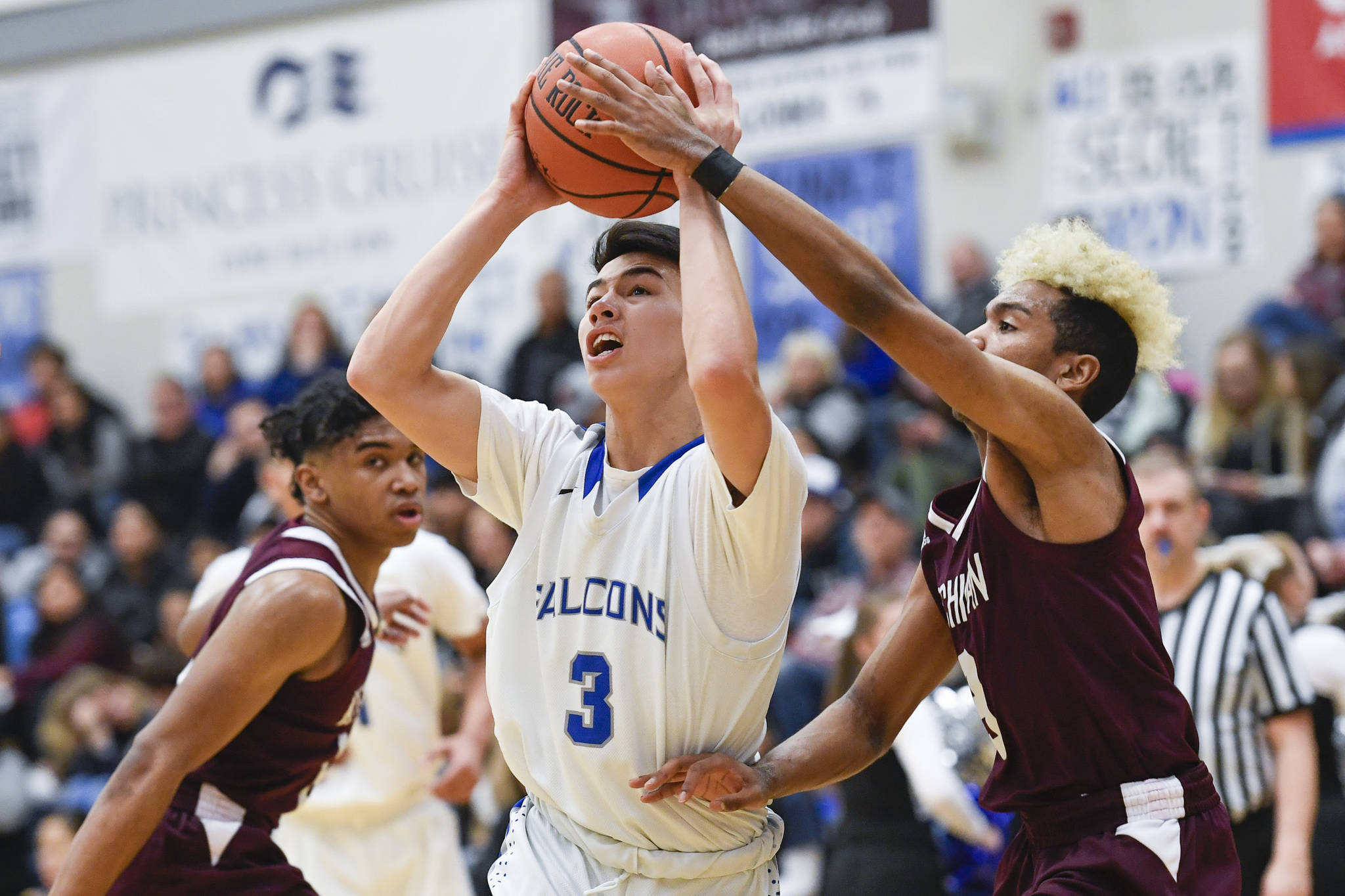 Thunder Mountain’s Bryson Echiverri, center, drives between Ketchikan brother Marcus Lee, right, and Chris Lee at TMHS on Friday, Feb. 8, 2019. TMHS won 62-55. (Michael Penn | Juneau Empire)