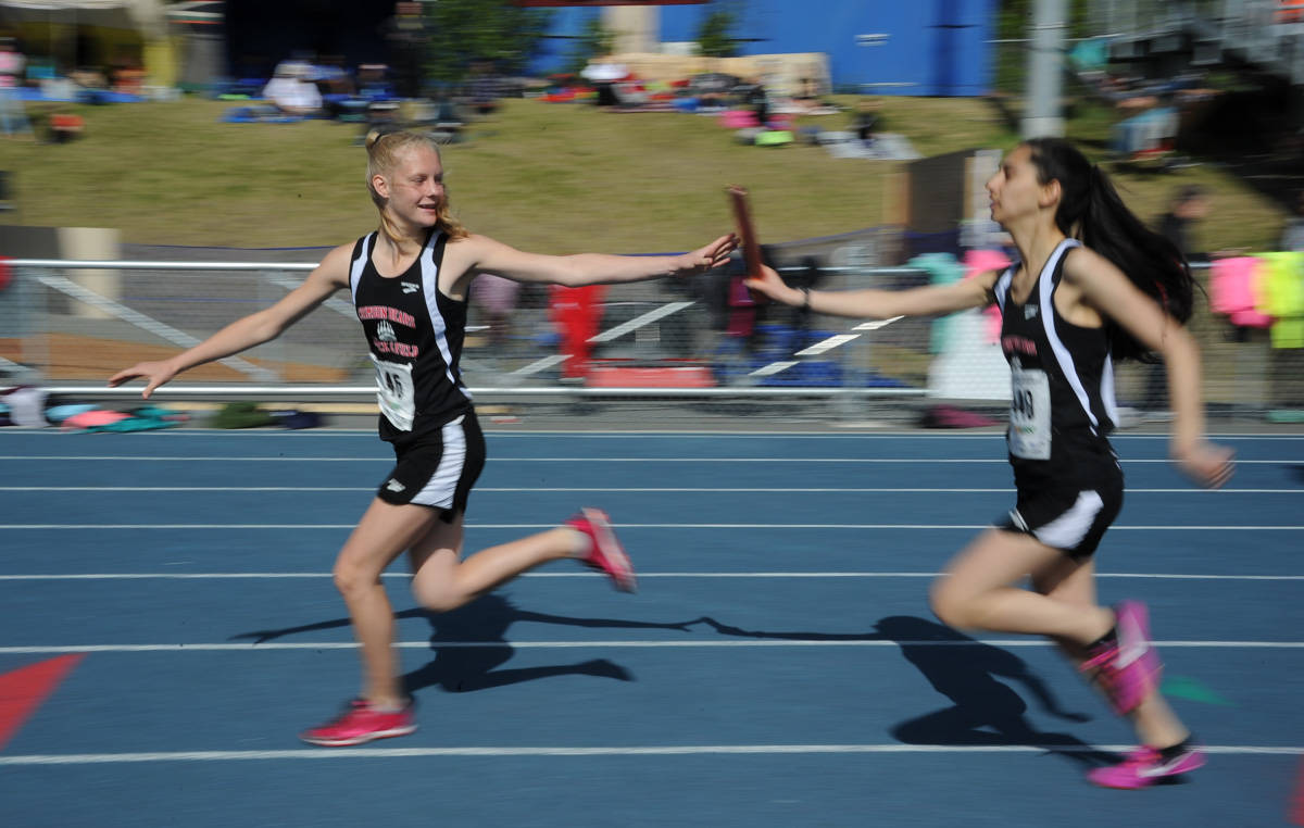 Juneau-Douglas High School’s Sadie Tuckwood receives the baton from Sosan Monsef during the 3200-meter relay at the state track and field championships at Palmer High School last May. The JDHS track and field team is projected to be strong in the distance events this season. (Michael Dinneen | For the Juneau Empire)