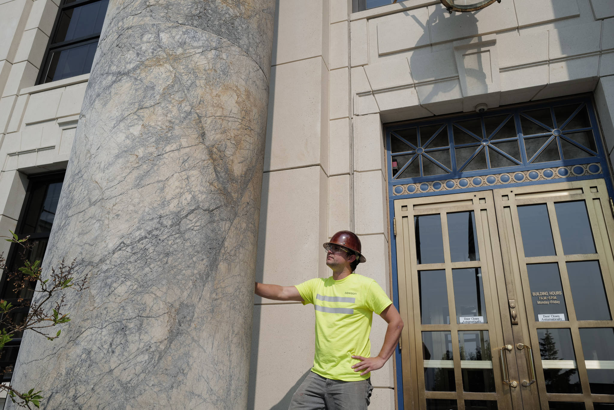 Jaron Wiley, a marble refinishing specialist for Dawson Construction, prepares the front of the Alaska State Capitol for scaffolding on Tuesday, July 2, 2019. The marble pillars, quarried in Tokeen, Alaska, will be sealed and ground smooth as part of the building’s remodeling project. (Michael Penn | Juneau Empire)