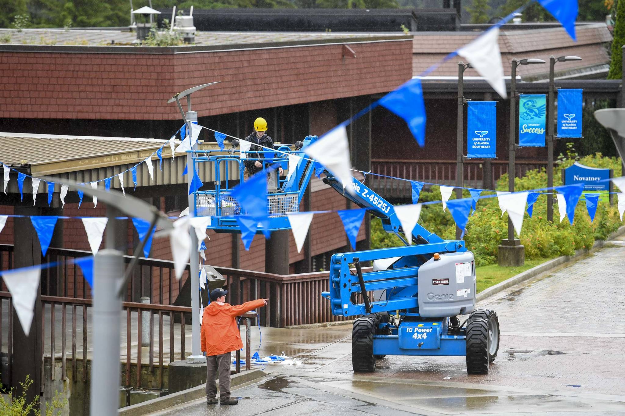 A crew hangs flags in the courtyard at the University of Alaska Southeast on Friday, Aug. 23, 2019. Classes start Monday, Aug. 26. (Michael Penn | Juneau Empire)
