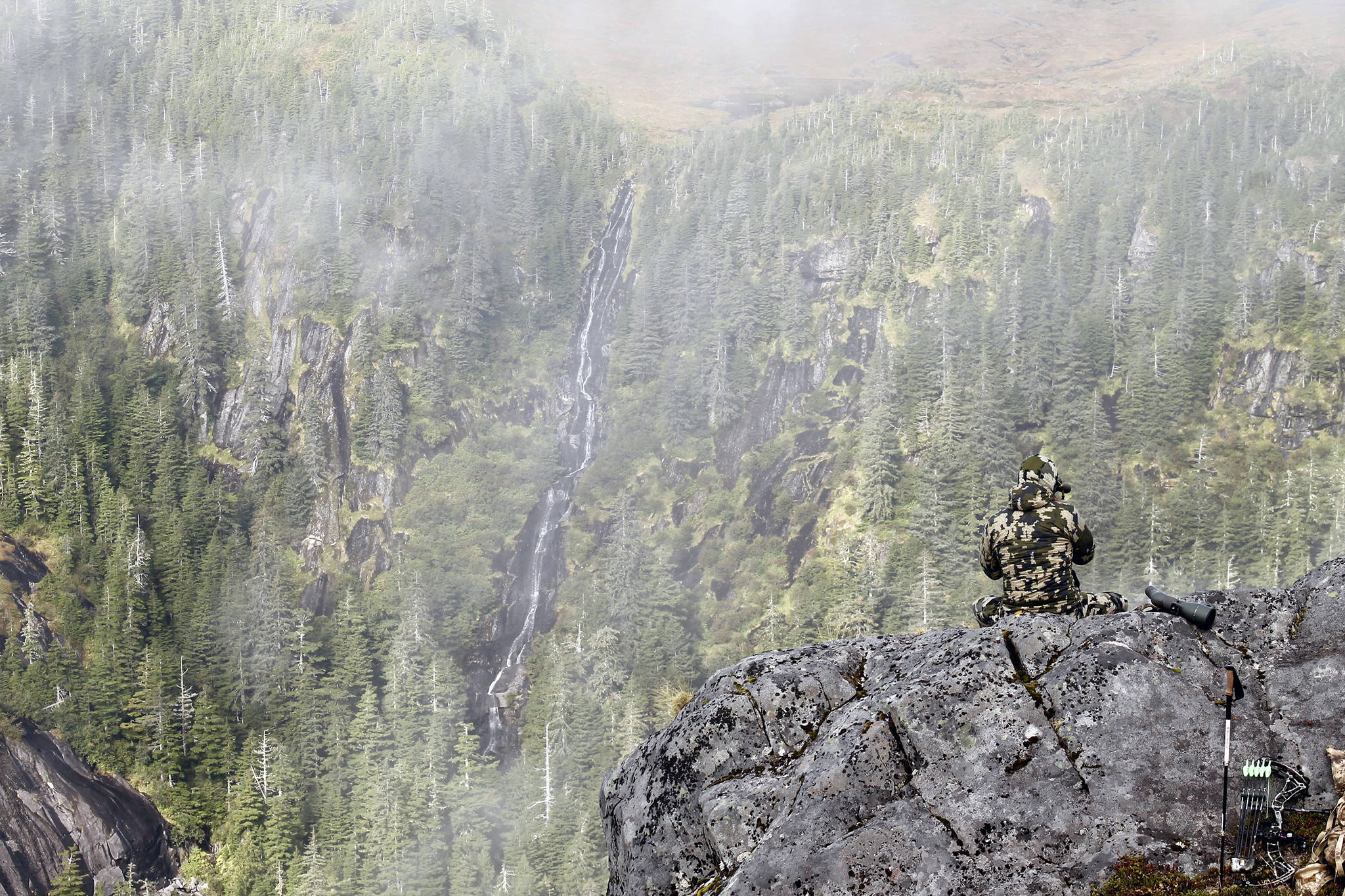 Ryan John look for a black bear on the side of Dude Mountain near Ketchikan Sunday afternoon. (Jeff Lund | For the Juneau Empire)