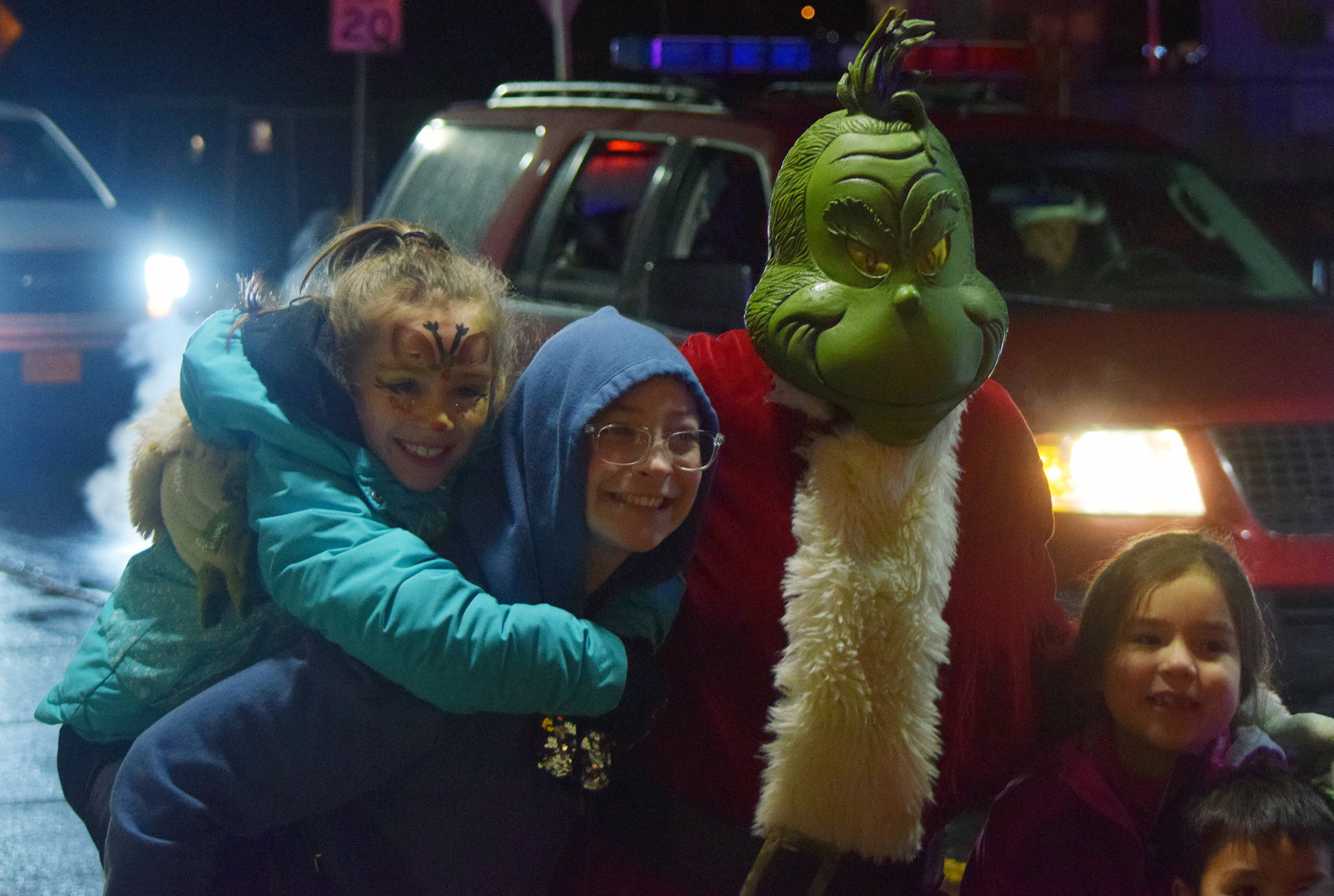 Miali Reid, Makinsey Morford and Lyndley Nakamura take a photo with the Grinch along South Franklin Street during the Capital City Fire/Rescue Santa Parade on Saturday, Dec. 21, 2019. (Nolin Ainsworth | Juneau Empire)