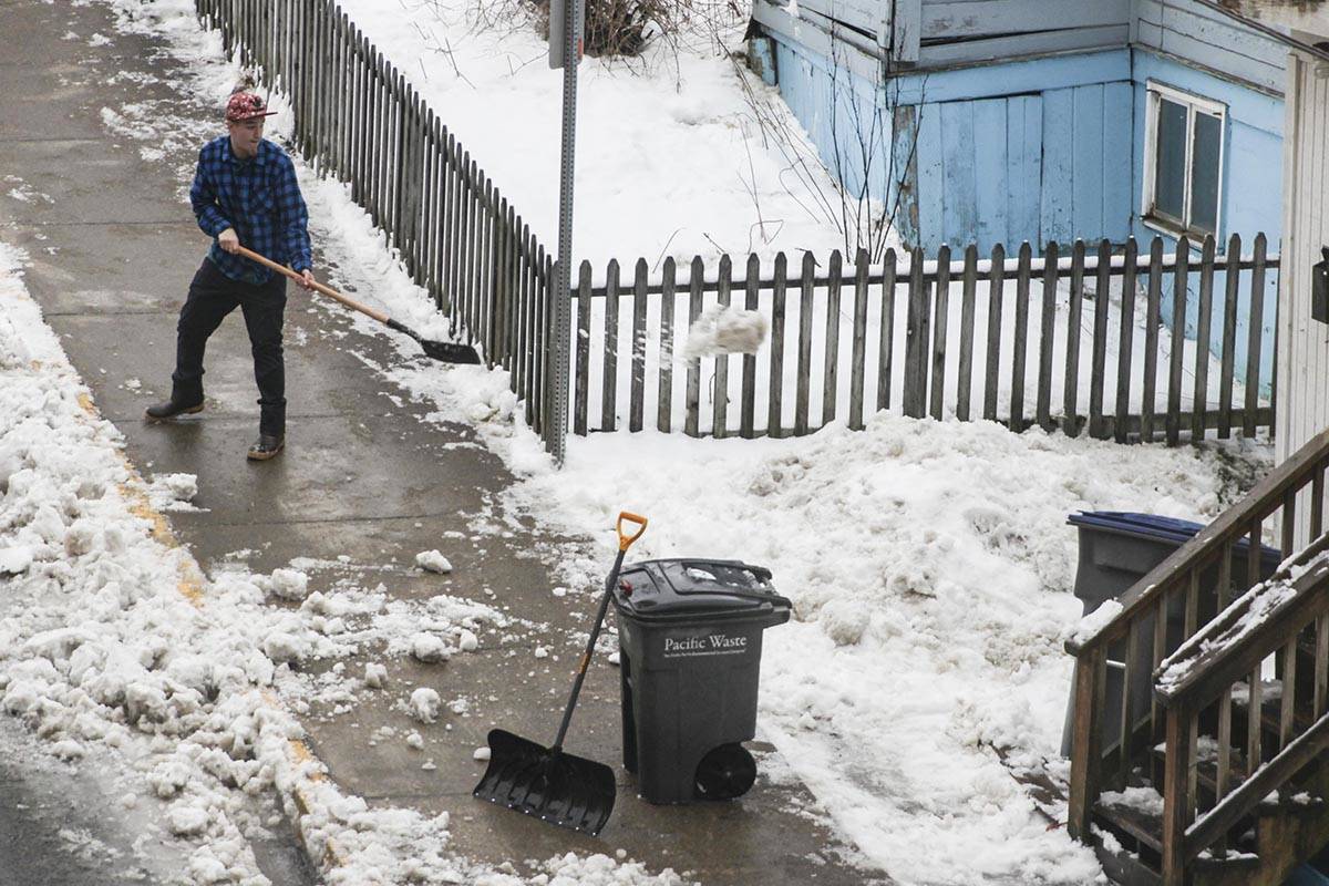 A man shovels snow near the state capitol as rising temperatures turn the roads to slush on Tuesday. (Michael S. Lockett | Juneau Empire)