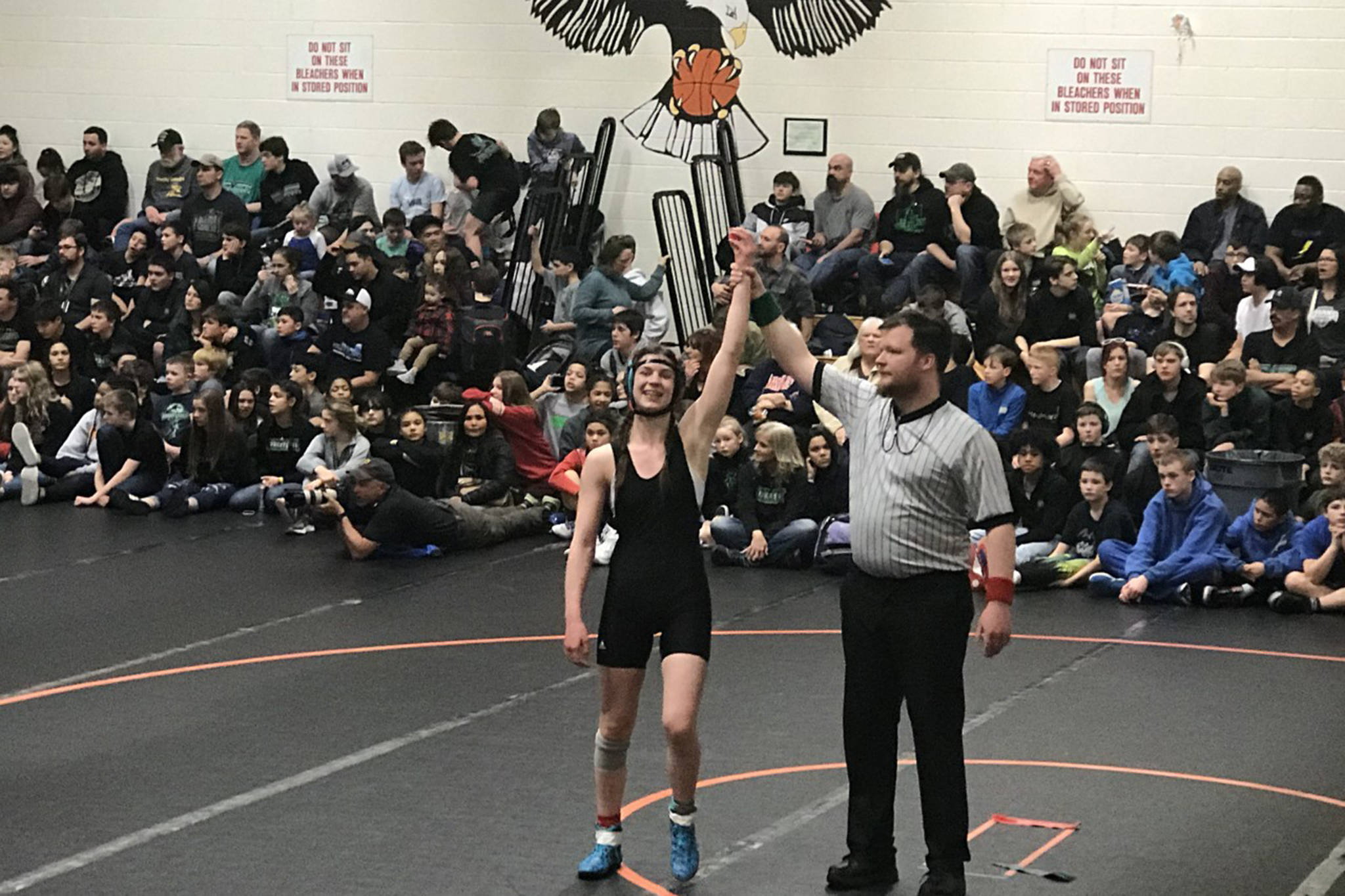 Evelyn Richards stands with her arm raised following a match at the Middle School State Wrestling Championship in Fairbanks. (Courtesy Photo | Dana Richards)