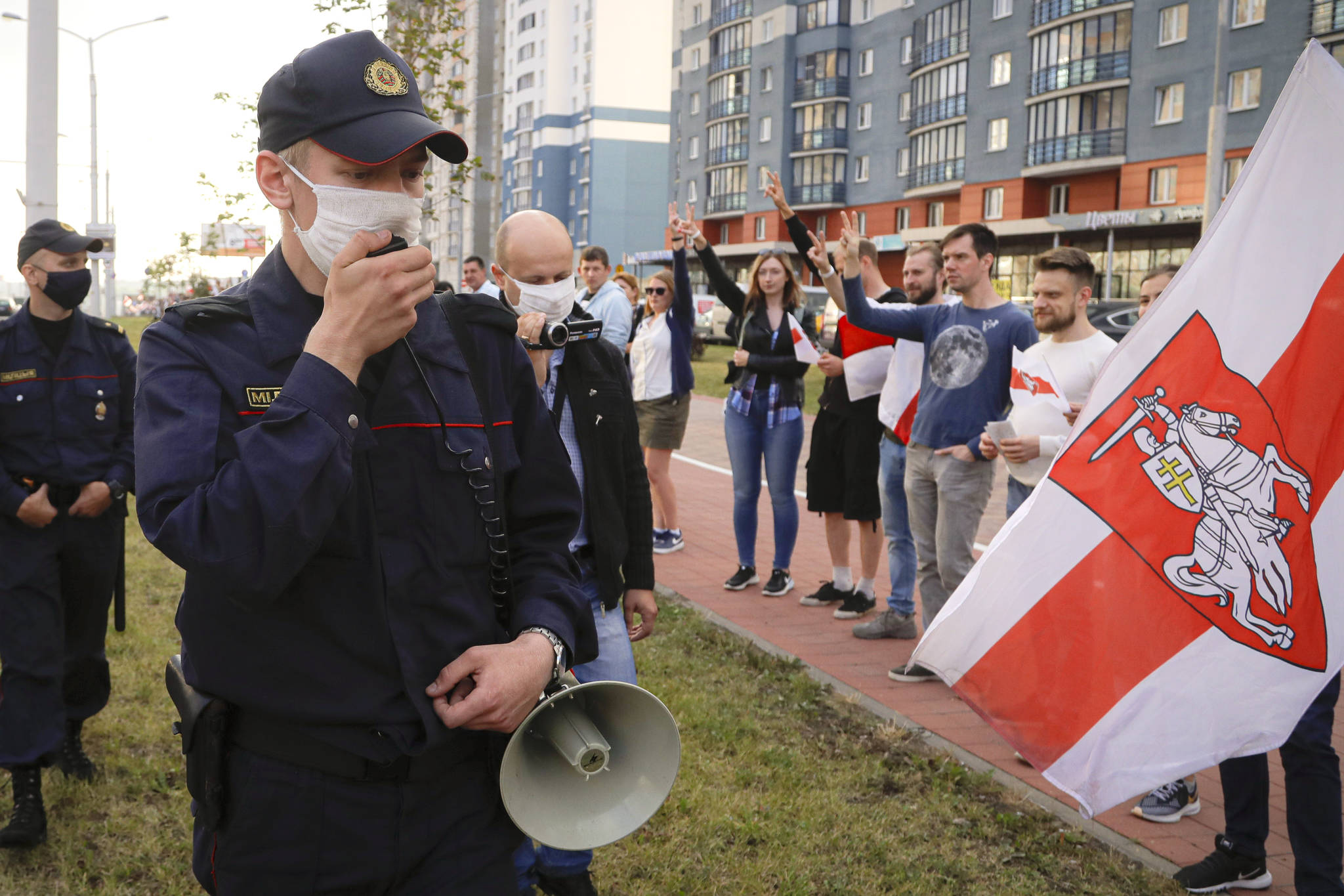 Supporters of the opposition flash victory signs as a police patrol walks by warning people that the protest is not authorized and asking them to leave in Minsk, Belarus, Friday, Aug. 21, 2020. Belarus’ authorities have detained a leader of striking factory workers and threatened protesters with criminal charges in a bid to stem massive protests challenging the extension of the 26-year rule of the country’s authoritarian president Alexander Lukashenko, who accused the U.S. of fomenting the unrest and vowed to see a quick end to protests. (AP Photo / Sergei Grits)