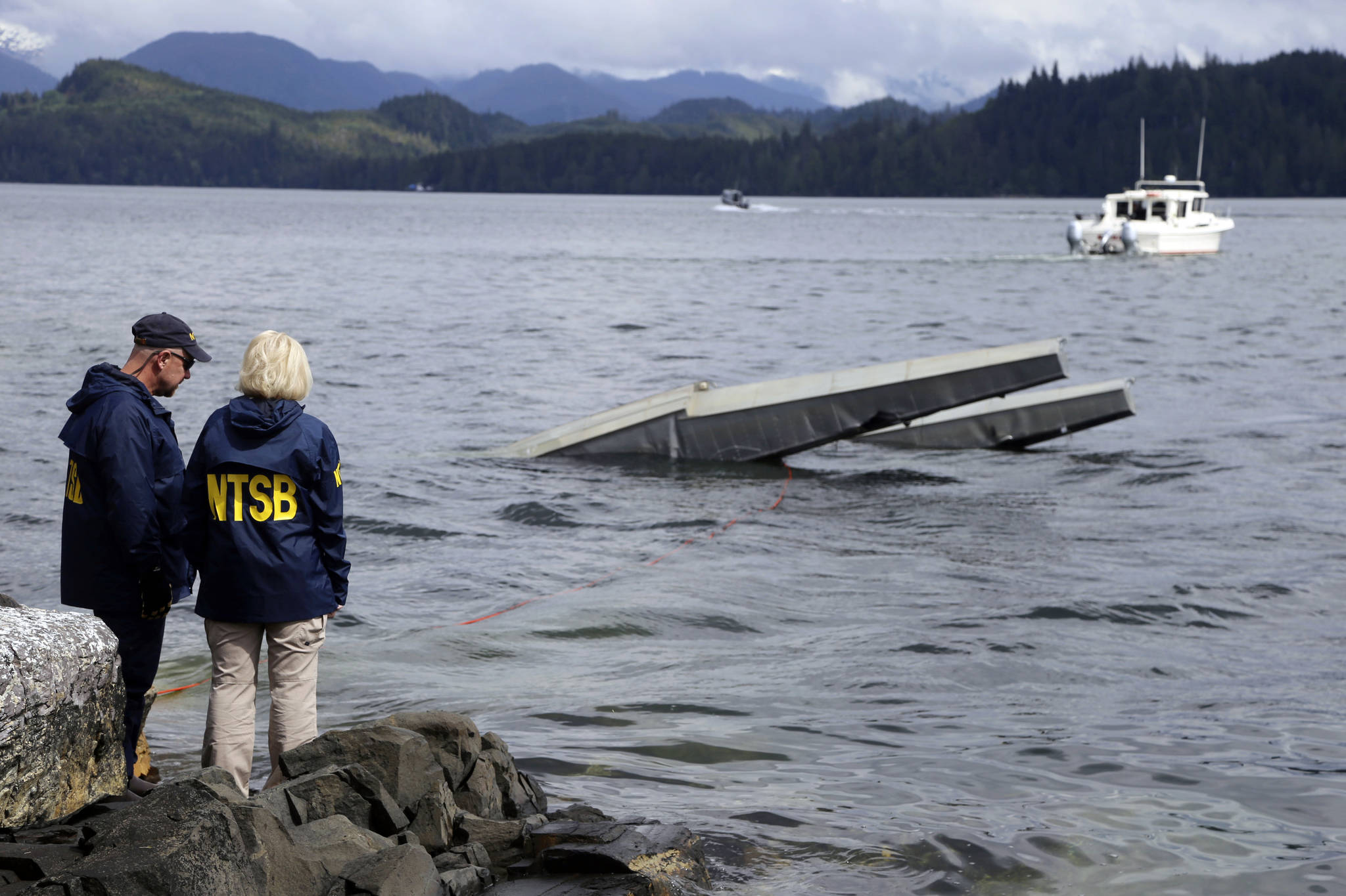 NTSB investigator Clint Crookshanks, left, and member Jennifer Homendy stand near the site of some of the wreckage of the DHC-2 Beaver, Wednesday, May 15, 2019, that was involved in a midair collision near Ketchikan, Alaska, a couple of days earlier. The pilots of two Alaskan sightseeing planes that collided in midair couldn’t see the other aircraft because airplane structures or a passenger blocked their views, and they didn’t get electronic alerts about close aircraft because safety systems weren’t working properly. That’s what the staff of the National Transportation Safety board found in their investigation. (Peter Knudson / NTSB)