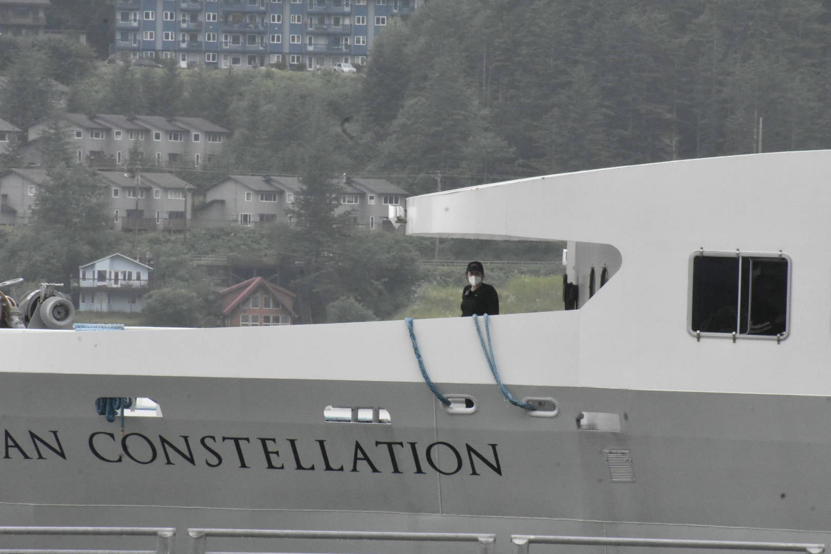 A person aboard the American Constellation wears a mask as the ship arrives late Monday afternoon at the downtown cruise docks. A cluster of COVID-19 cases associated with the ship has reached 10. All known cases in the cluster are isolating. (Peter Segall / Juneau Empire)