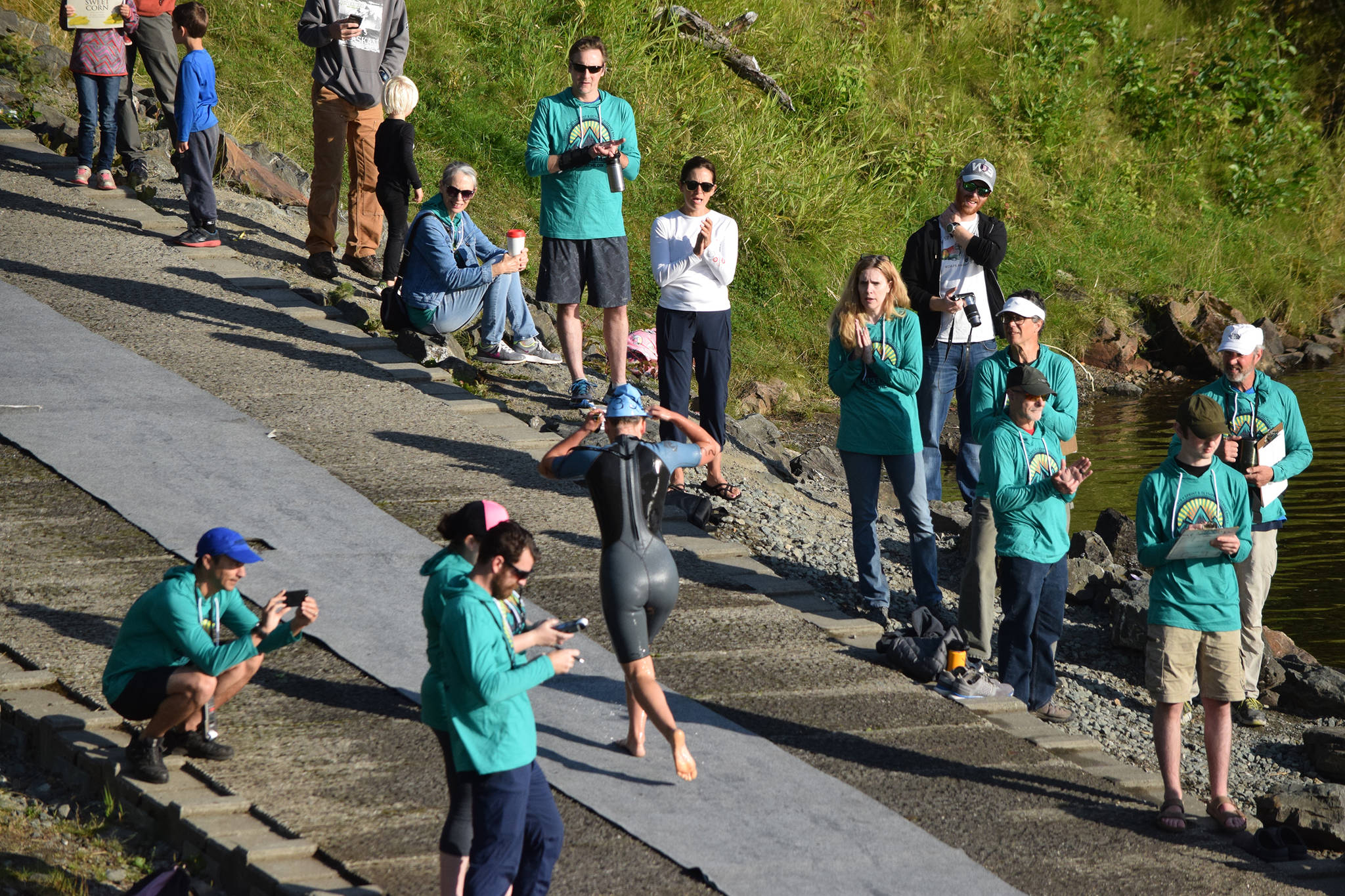 Aukeman Triathlon supporters and volunteers cheer on a swimmer as they leave Auke Lake on Saturday, Aug. 3, 2019. Juneau is being considered to host a three-year series of Ironman triathlons, the first of which wold be held next August. (Nolin Ainsworth/Juneau Empire File)