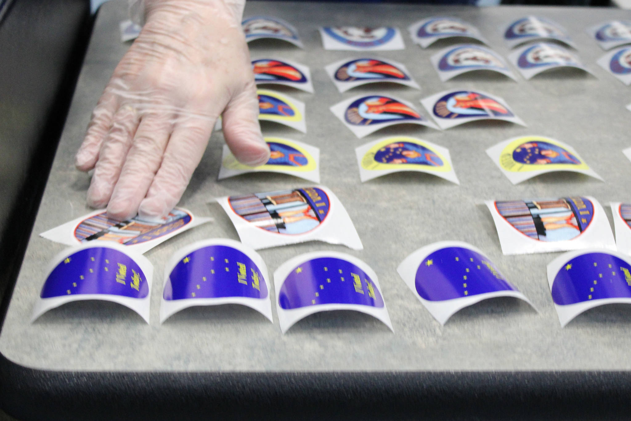 An election official lays out more "I voted" stickers on Tuesday, Nov. 3. Stickers for the 2020 general election featured designs by Alaskan artist Barbara Lavallee. Election officials in Juneau said the sticker depicting a pair of Neoprene boots ha been particularly popular. (Ben Hohenstatt / Juneau Empire)