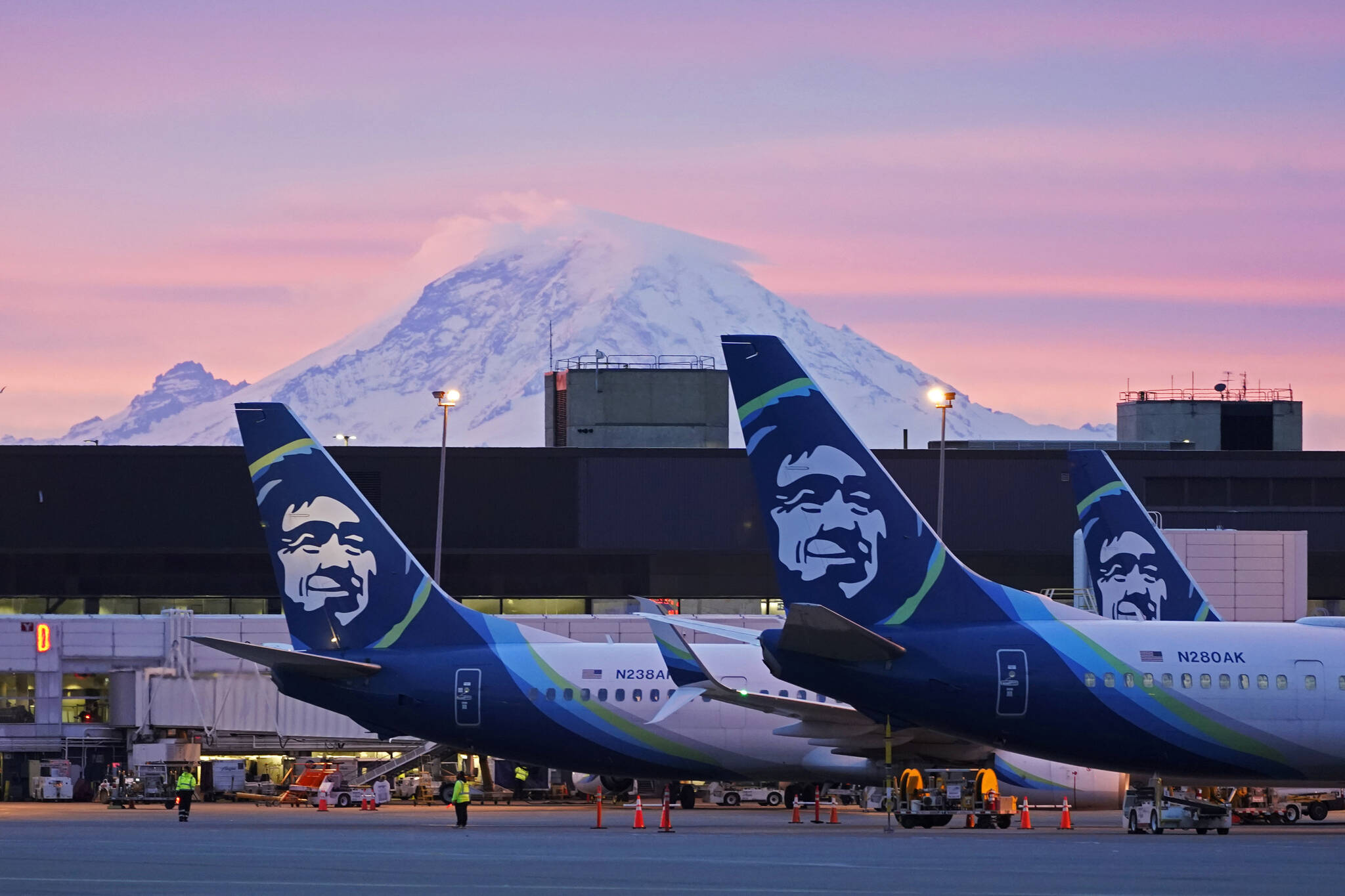 Alaska Airlines planes are shown parked at gates with Mount Rainier in the background at sunrise, at Seattle-Tacoma International Airport in Seattle. Alaska Air Group has told its 22,000 employees they will be required to get a COVID-19 vaccination. There are some exceptions to the policy, which has shifted since last month, the The Seattle Times reported. In an email Thursday evening to all Alaska Airlines and Horizon Air employees, the Seattle-based company said employees will now be required to be fully vaccinated or approved for a reasonable accommodation. (AP Photo / Ted S. Warren)