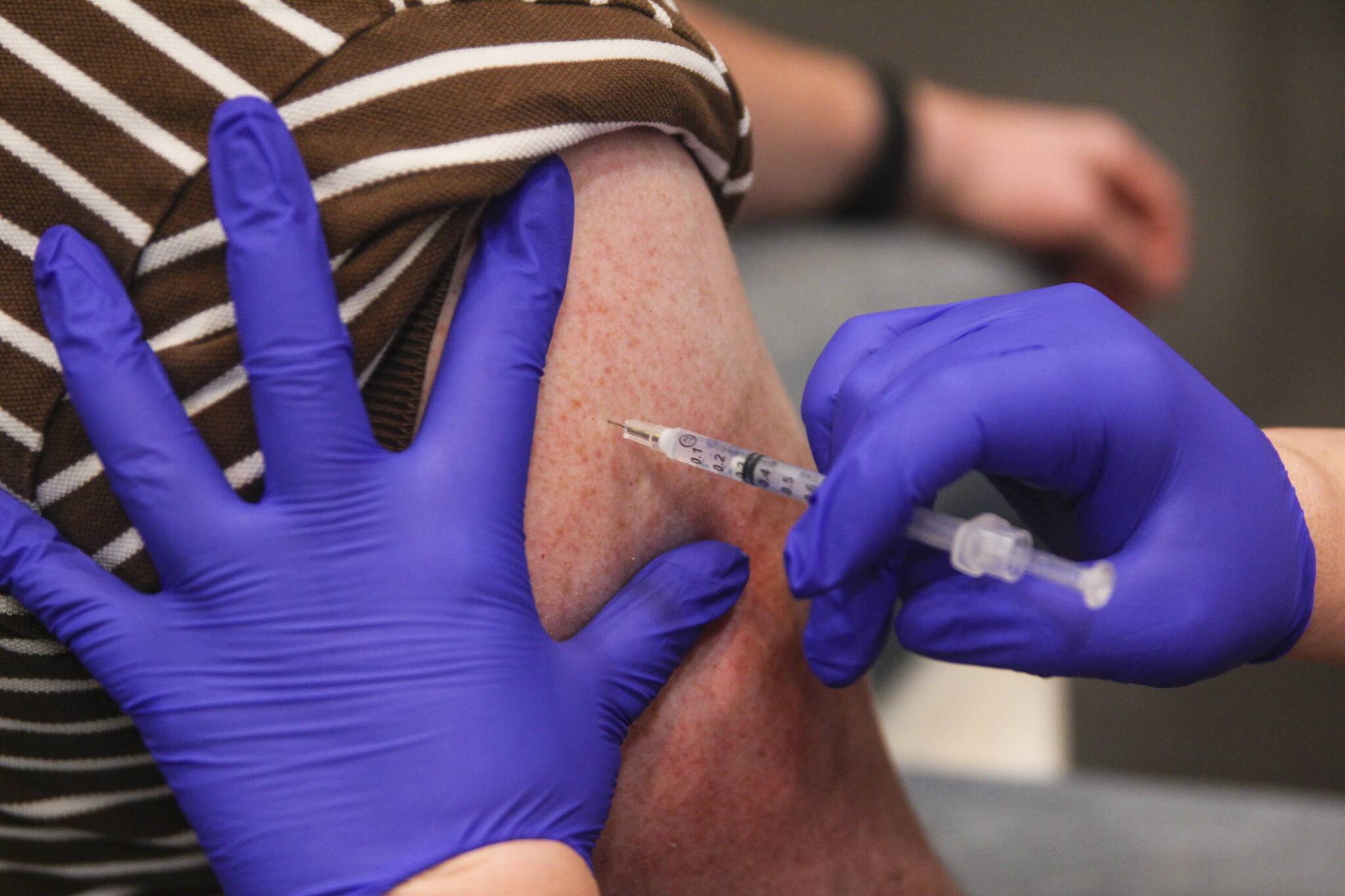 A Juneau resident receives the booster shot for the Pfizer coronavirus vaccine at Centennial Hall on Oct. 2, 2021. More than 1,300 Juneau residents received booster shots at the clinic. (Michael S. Lockett / Juneau Empire)