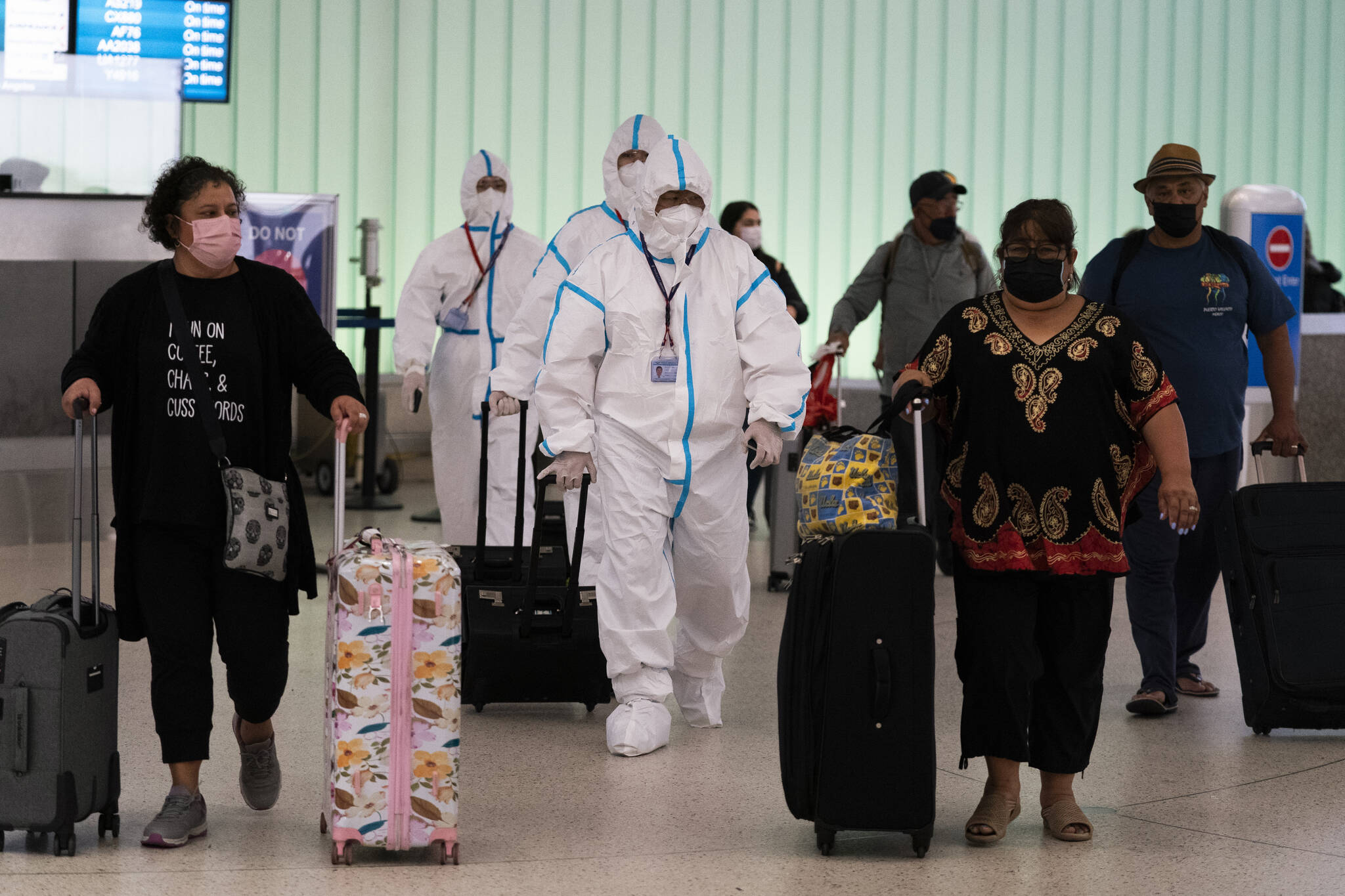 Air China flight crew members in hazmat suits walk through the arrivals area at Los Angeles International Airport in Los Angeles, Tuesday, Nov. 30, 2021, on Wednesday, California reported the first U.S. case of the omicron variant. Brazil and Japan joined the rapidly widening circle of countries to report cases of the omicron variant of the coronavirus on Tuesday. (AP Photo/Jae C. Hong)