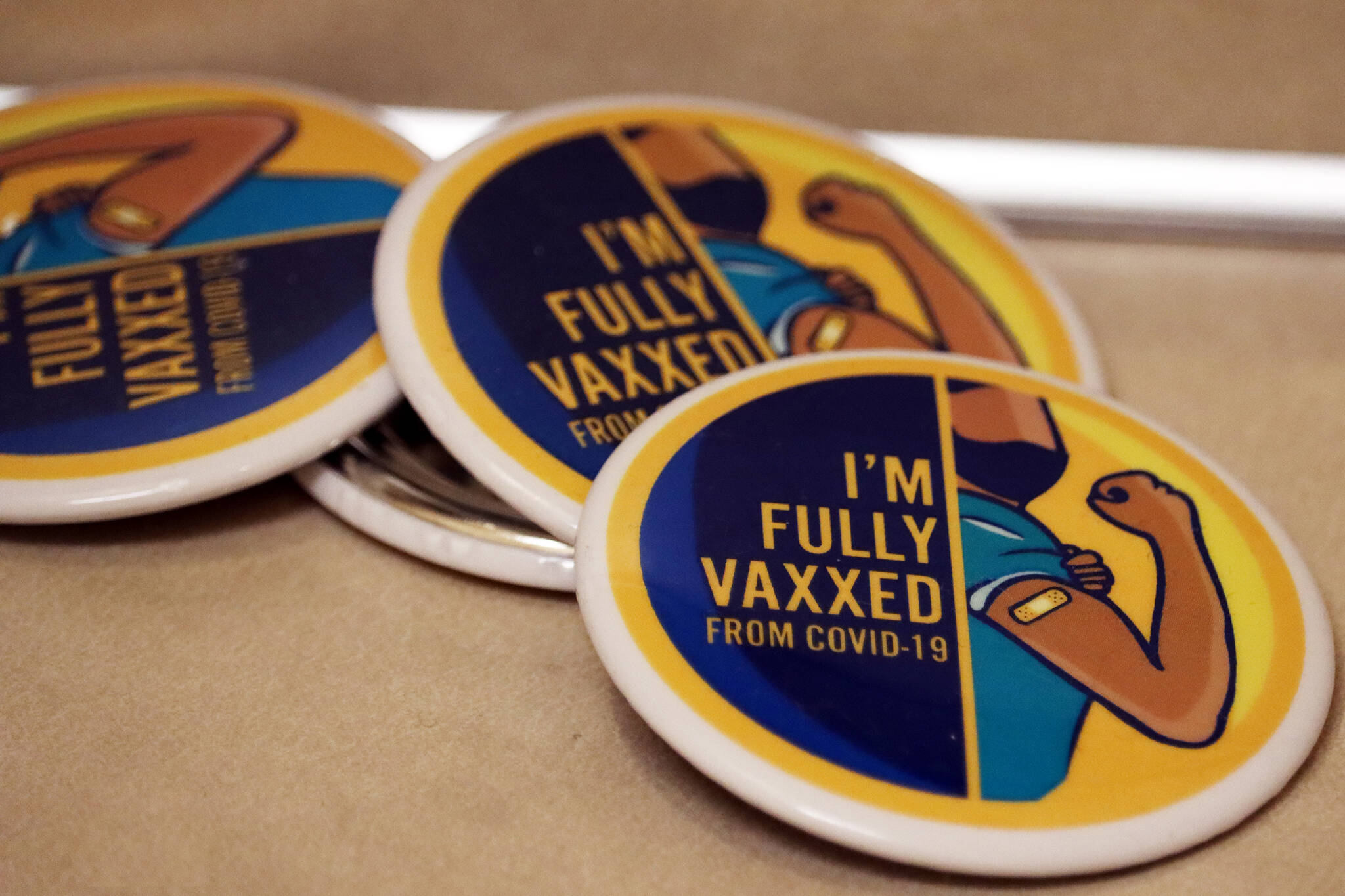 Buttons boasting of fully vaccinated status sit on a counter top at Juneau Public Health Center. (Ben Hohenstatt / Juneau Empire)