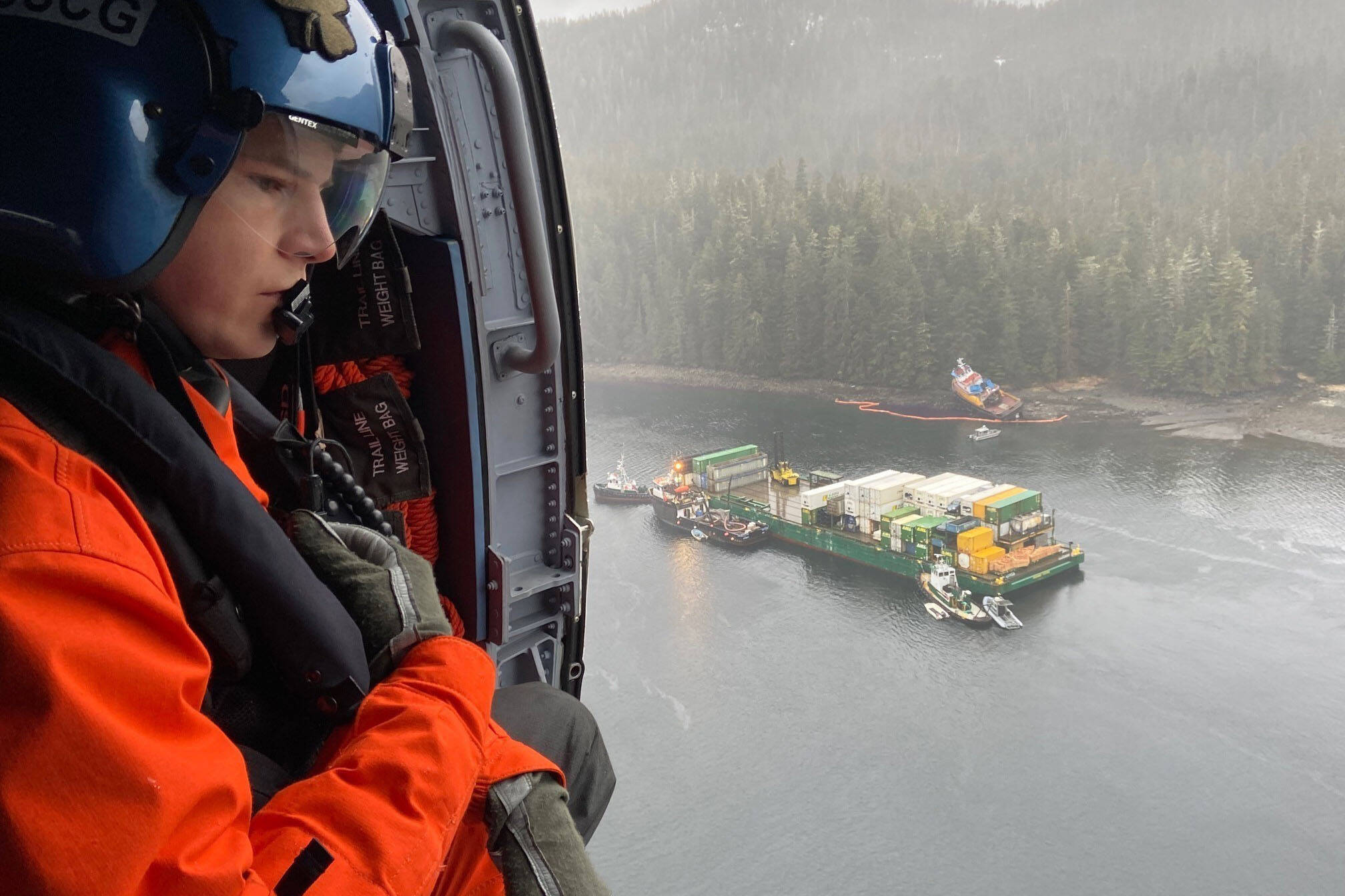 Petty Officer 3rd Class Christopher Daniel, an aviation maintenance technician at Air Station Sitka, observes an oil sheen surrounding the Western Mariner, an 83-foot inspected tug, in Neva Strait March, 21, 2022. (U.S. Coast Guard / Petty Officer 1st Class Brian Wereda)