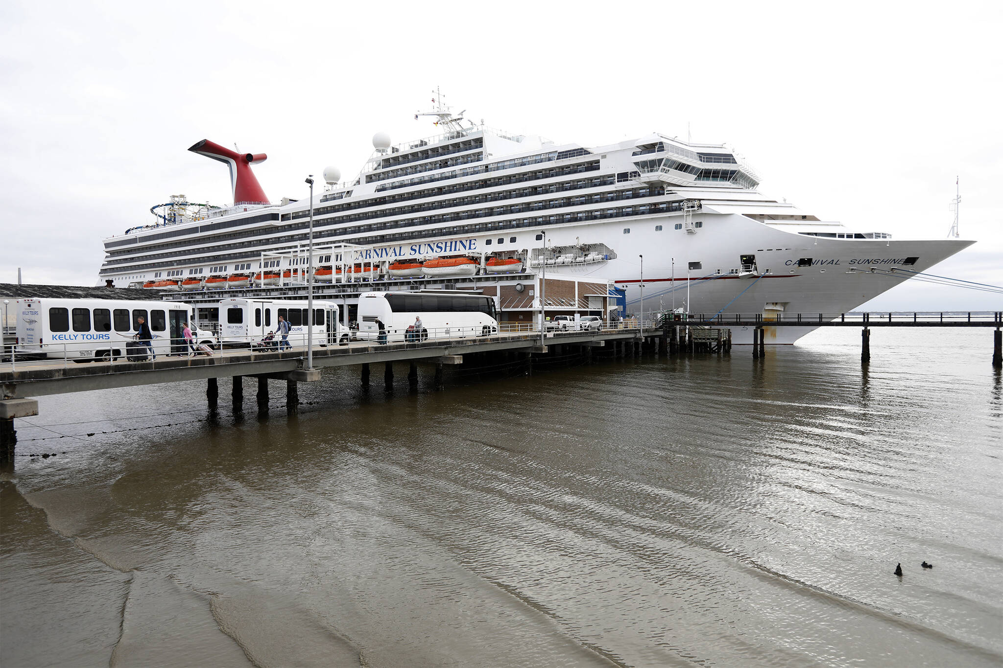 Passengers disembark from the Carnival Sunshine cruise ship Monday, March 16, 2020, in Charleston, S.C. Federal officials are dropping a health warning that they have attached to sailing on cruise ships since the start of the pandemic. The U.S. Centers for Disease Control and Prevention said Wednesday, March 30, 2022 that they will leave it up to vacationers to decide whether they feel safe getting on a ship. (AP Photo / Mic Smith)