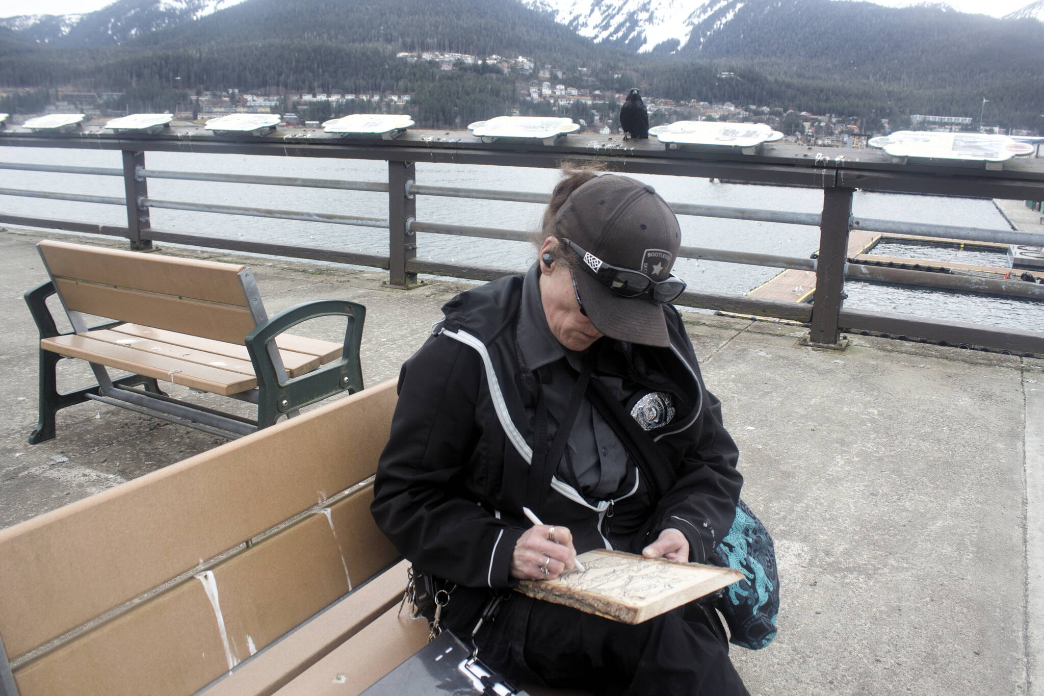 Mark Sabbatini / Juneau Empire 
Amy Purvis, a private security officer who’s been a Juneau resident since 2000, sketches a heart and rose for a piece of woodburning art she hopes to sell to tourists this summer on the still mostly empty pier at Marine Park on Friday.