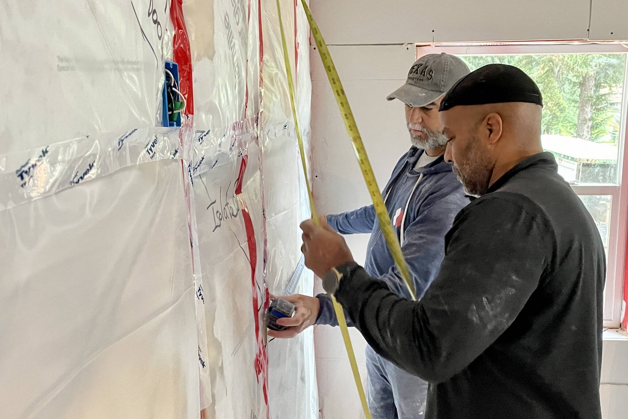 Chris Cotton, in black, and Matthew Wetherholt measure off distance in a house they and other members of Team Rubicon, a disaster-recovery nonprofit, are helping to restore following the Haines landslide of 2020. (Michael S. Lockett / Juneau Empire)