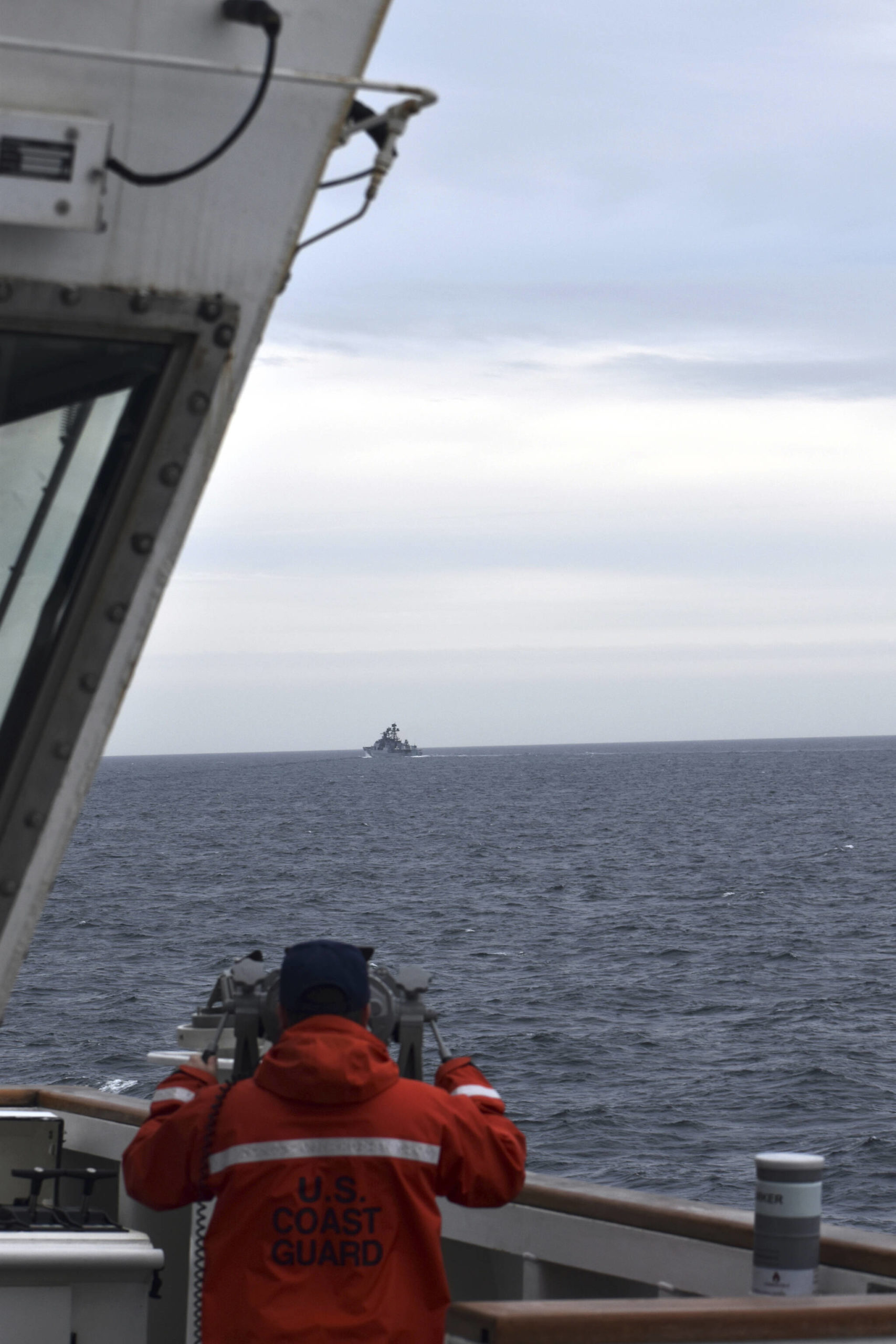 In this photo provided by the U.S. Coast Guard, a Coast Guard Cutter Kimball crew-member observes a foreign vessel in the Bering Sea, Monday, Sept. 19, 2022. The U.S. Coast Guard cutter on routine patrol in the Bering Sea came across the guided missile cruiser from the People’s Republic of China, officials said Monday, Sept. 26. (U.S. Coast Guard District 17 via AP)