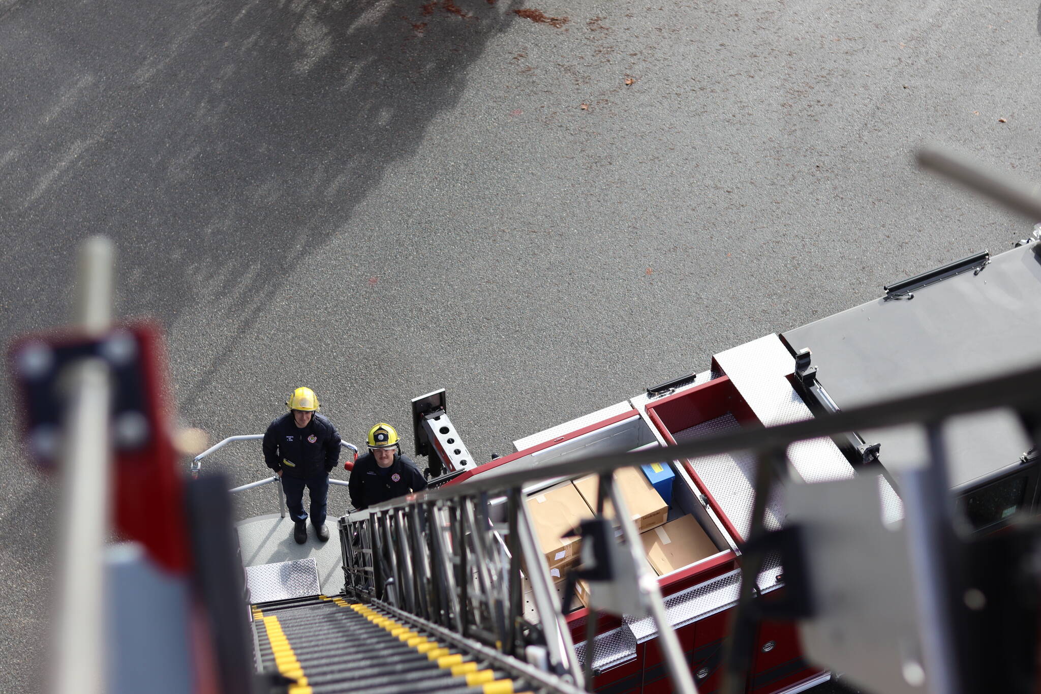 Capital City Fire/Rescue engineer Peter Flynn and firefighter Connor Hoyt stand at the bottom of the department’s new truck ladder on Thursday, Oct. 6 during training operations at the Glacier Fire Station. (Jonson Kuhn / Juneau Empire)