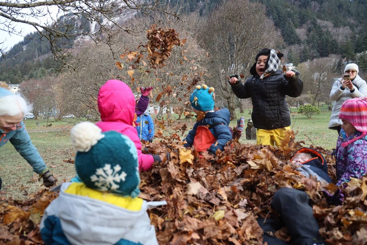 KinderReady Preschool students from Harborview Elementary frolic in a pile of dried leaves at Evergreen Cemetery on Tuesday. The leaf pile is an annual event organized by Linda Torgerson and has been happening in Juneau for around 25 years. (Clarise Larson / Juneau Empire)