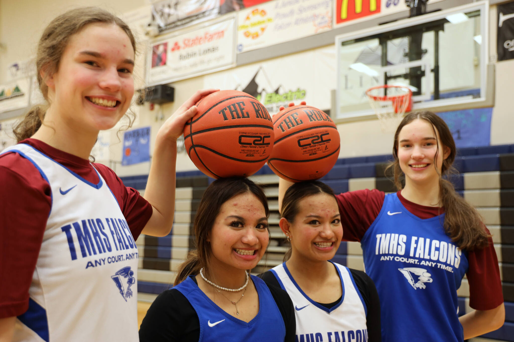 Sophomore twins Cailynn and Kerra Baxter, outside, and juniors twins Jaya and MikahCarandang, inside, smile for a picture after their Monday night practice at Thunder Mountain High School. (Clarise Larson / Juneau Empire)