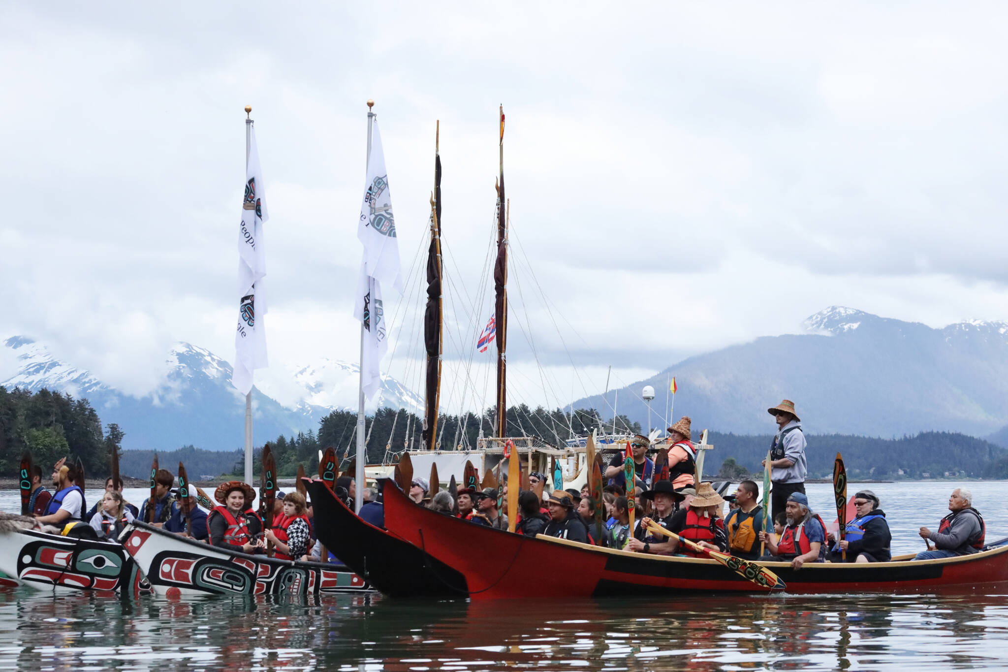 Crew members of the Moananuiākea voyage from the Hōkūle‘a canoe paddle to the shore of Auke Bay as they are welcomed Saturday afternoon by Juneau residents and tribal leaders. (Clarise Larson / Juneau Empire)