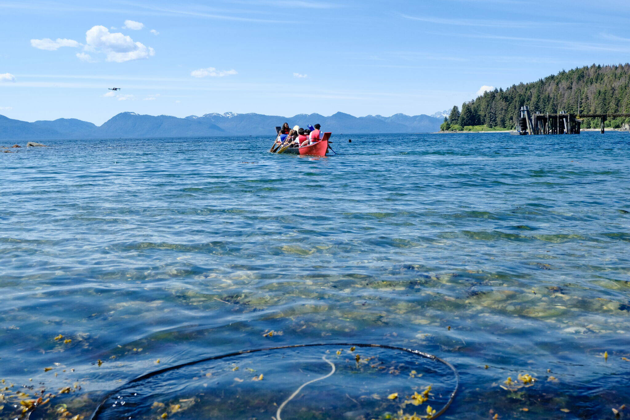 Angoon students paddle their dugout, war-style canoe into Chatham Strait from Front Street on June 19. (Photo by Claire Stremple/Alaska Beacon)