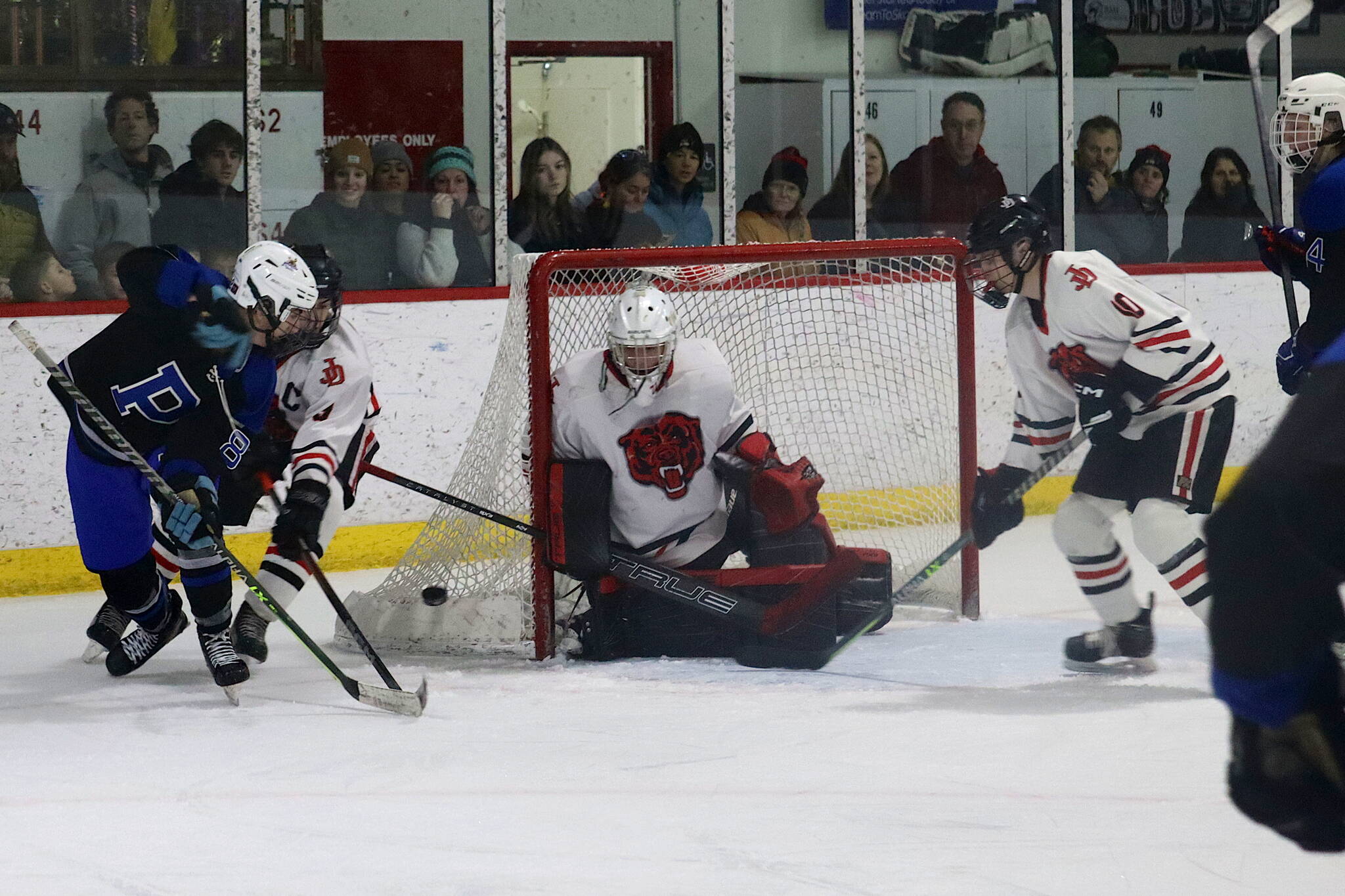 Juneau and Palmer players fight for the puck near the Crimson Bears’ goal during Saturday night’s game between Juneau-Douglas High School: Yadaa.at Kalé and Palmer High School at Treadwell Arena. (Mark Sabbatini / Juneau Empire)