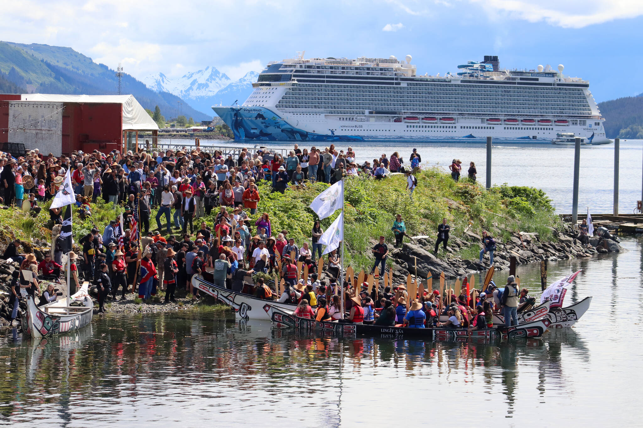 Canoes from communities south of Juneau led by the One People Canoe Society land downtown on Tuesday to cheers and songs from people on shore. (Jasz Garrett / Juneau Empire)