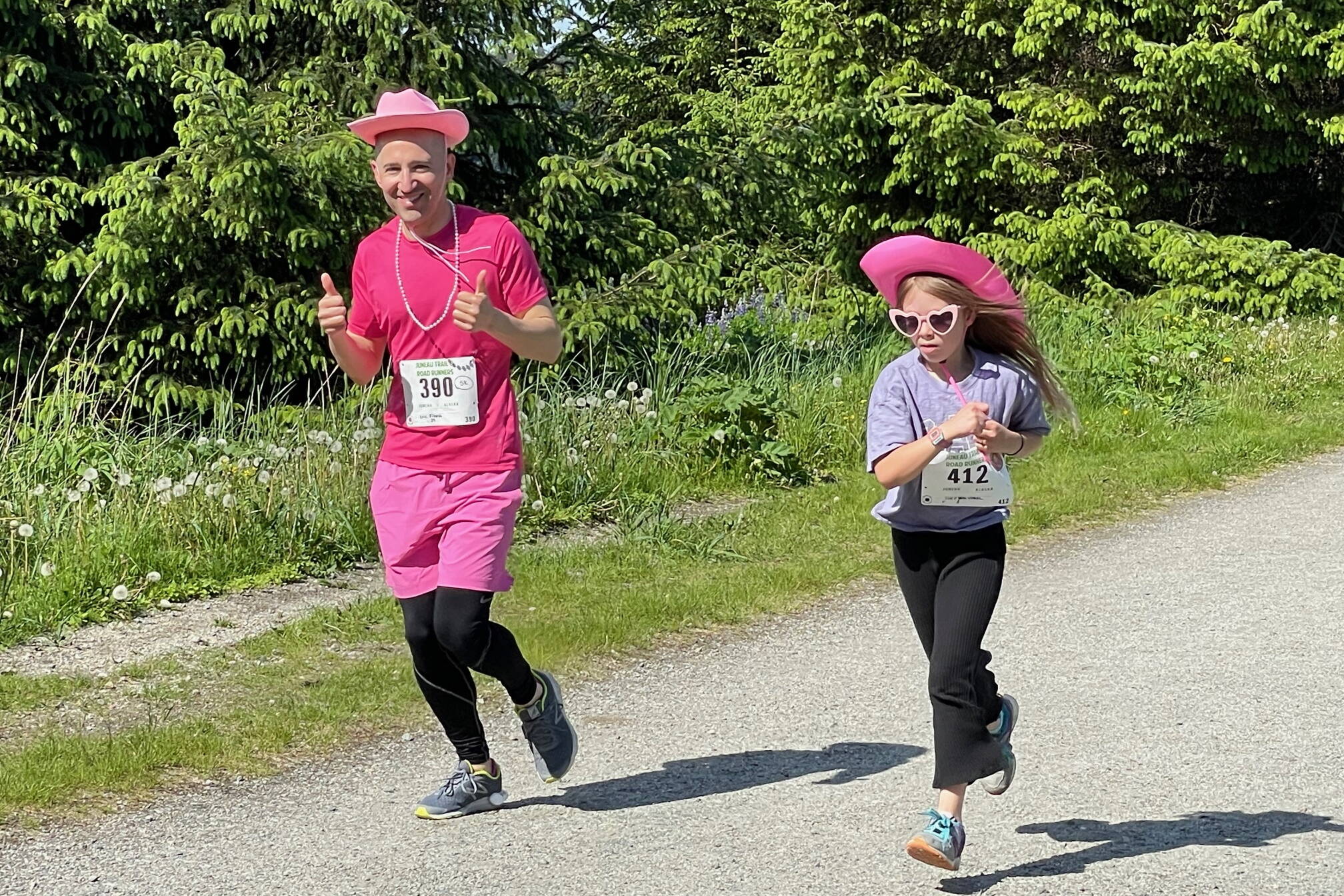 In the spirit of Dolly Parton’s country music roots, race participant Mendenhall River Community School Principal Eric Filardi runs in costume with young Lucy Vogel wearing heart-shaped sunglasses as they enjoy the sunny Saturday weather on the Airport Dike Trail race course. About 85 runners participated, many wearing pearls and pink hats provided at the starting tent. (Laurie Craig / Juneau Empire)