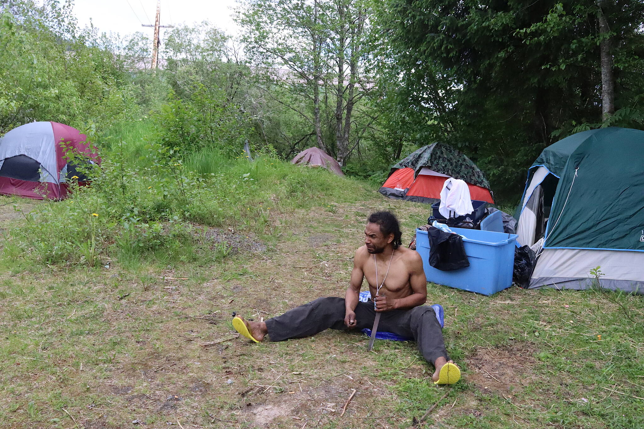 Curtis Davis sharpens a spike at his makeshift campsite near Juneau International Airport on Sunday. (Mark Sabbatini / Juneau Empire)