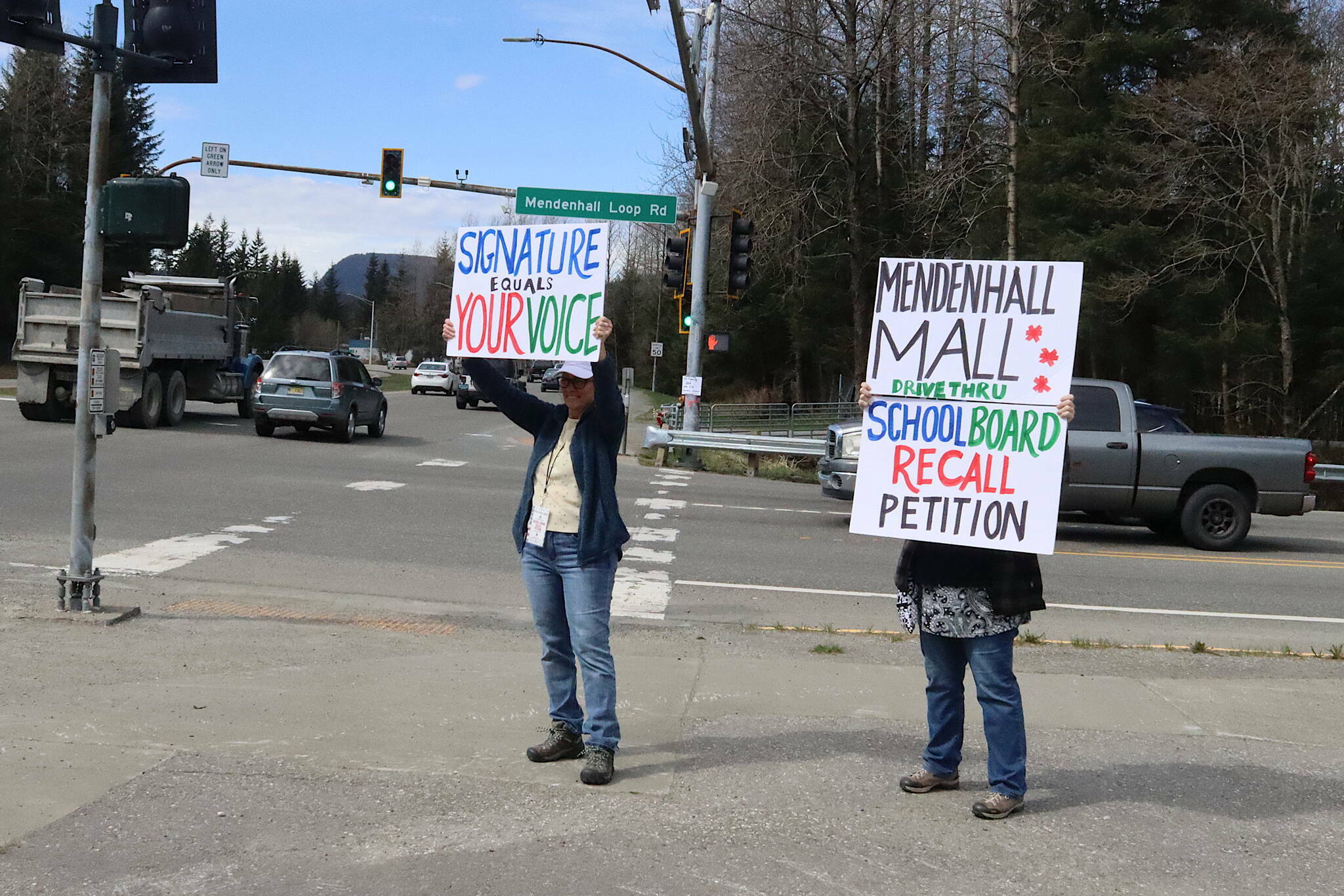 Shannan Greene (left) and Sharyn Augustine hold signs on April 27 urging residents to sign recall petitions for Juneau Board of Education President Deedie Sorensen and Vice President Emil Mackey due to their roles in a budget crisis for the current fiscal year. (Mark Sabbatini / Juneau Empire file photo)