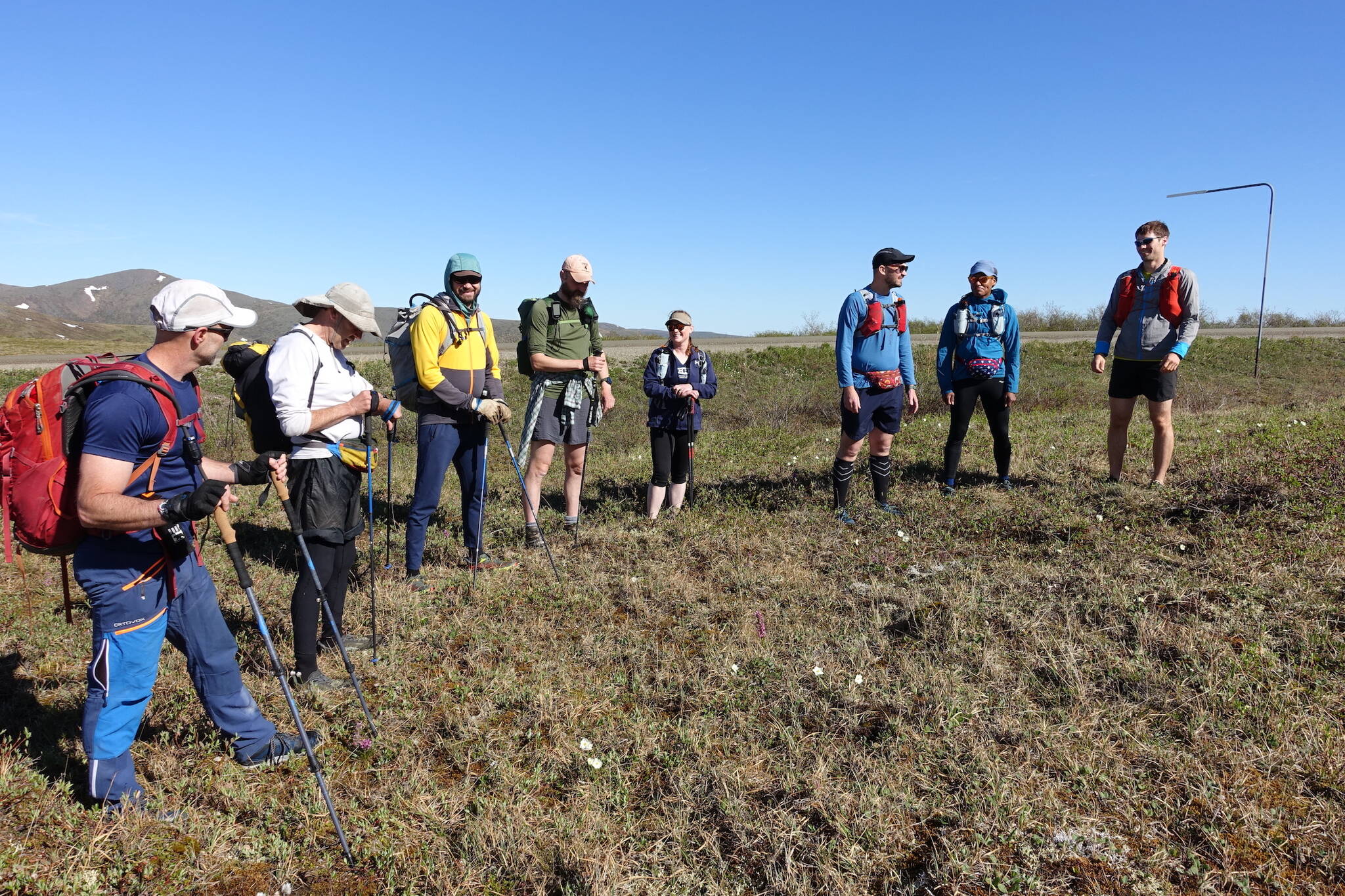 Competitors in the AlaskAcross 2024 race prepare to depart from Eagle Summit at 10 a.m. on June 8, 2024. From left are Bruno Grunau, Mark Ross, Forest Wagner, Mike Fisher, Sarah Hurkett, Clinton Brown, Tracie Curry and Curtis Henry. (Photo by Ned Rozell)