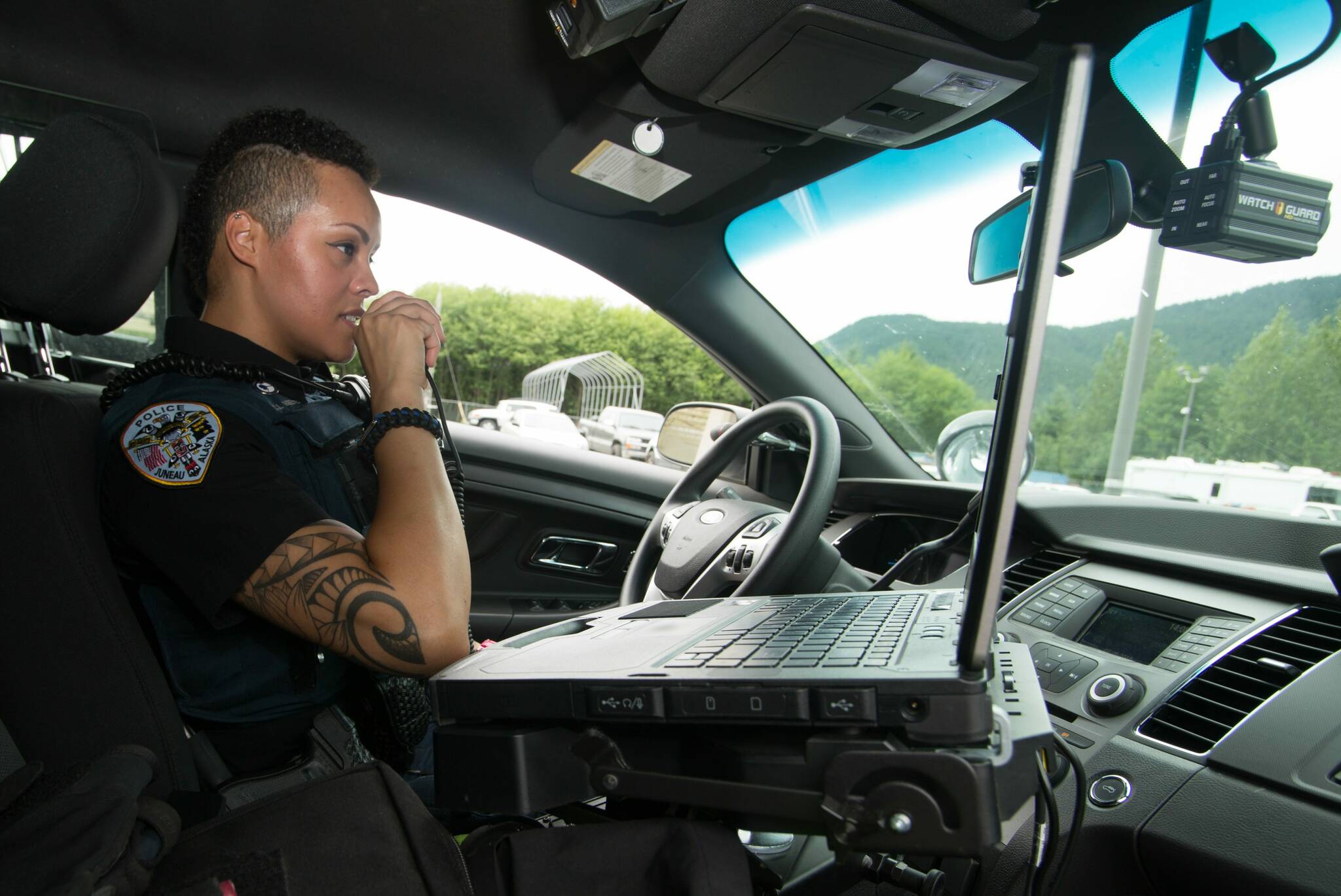 A Juneau Police Department officer talks on a radio in a patrol car. Officials said JPD’s communications system, which had an end-of-life date in 2014, needs to be replaced to provide improvements such as full radio coverage within the city and borough limits. (City and Borough of Juneau photo)